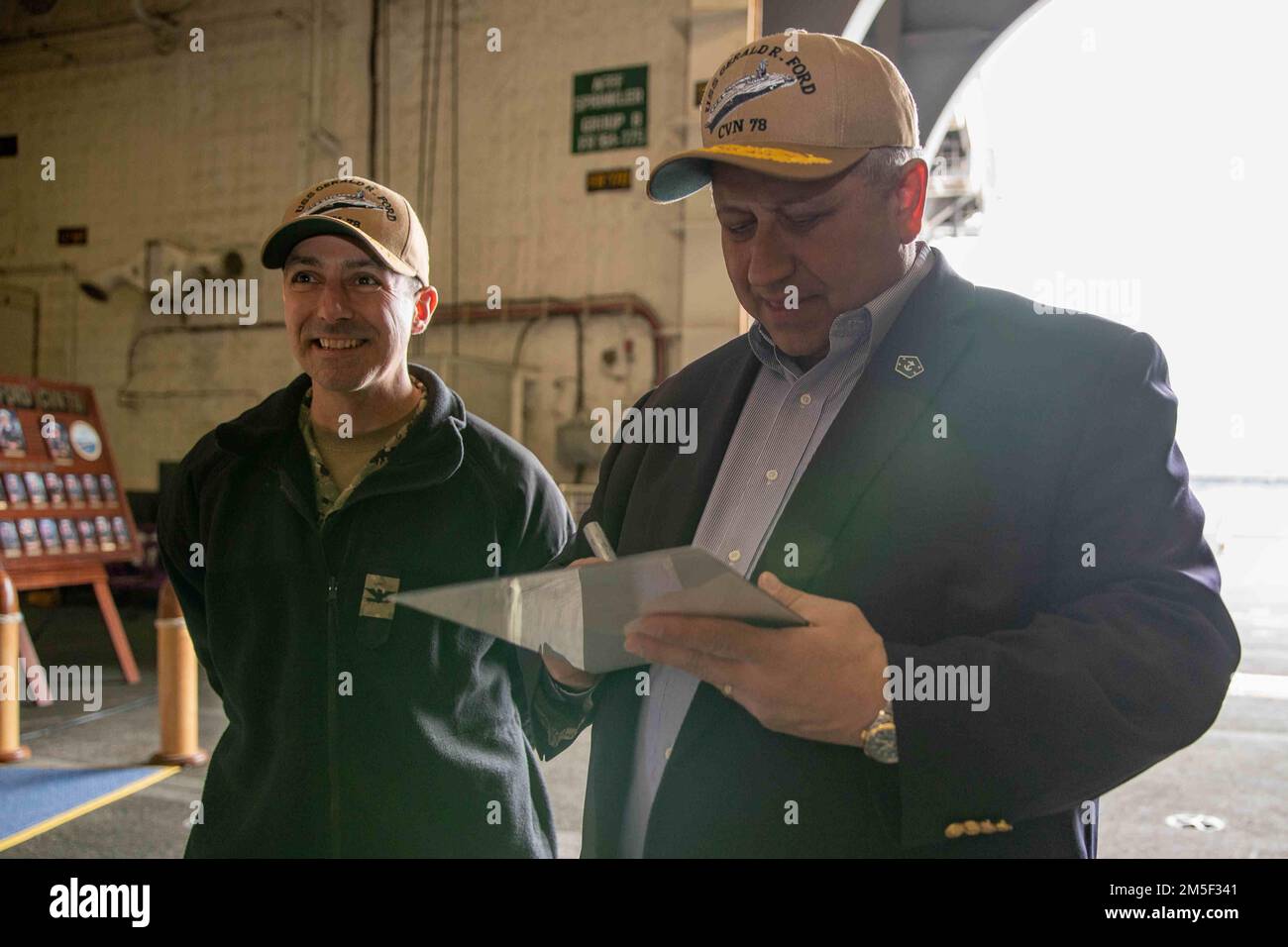 Secretary of the Navy Carlos Del Toro, right, autographs a portrait of ...