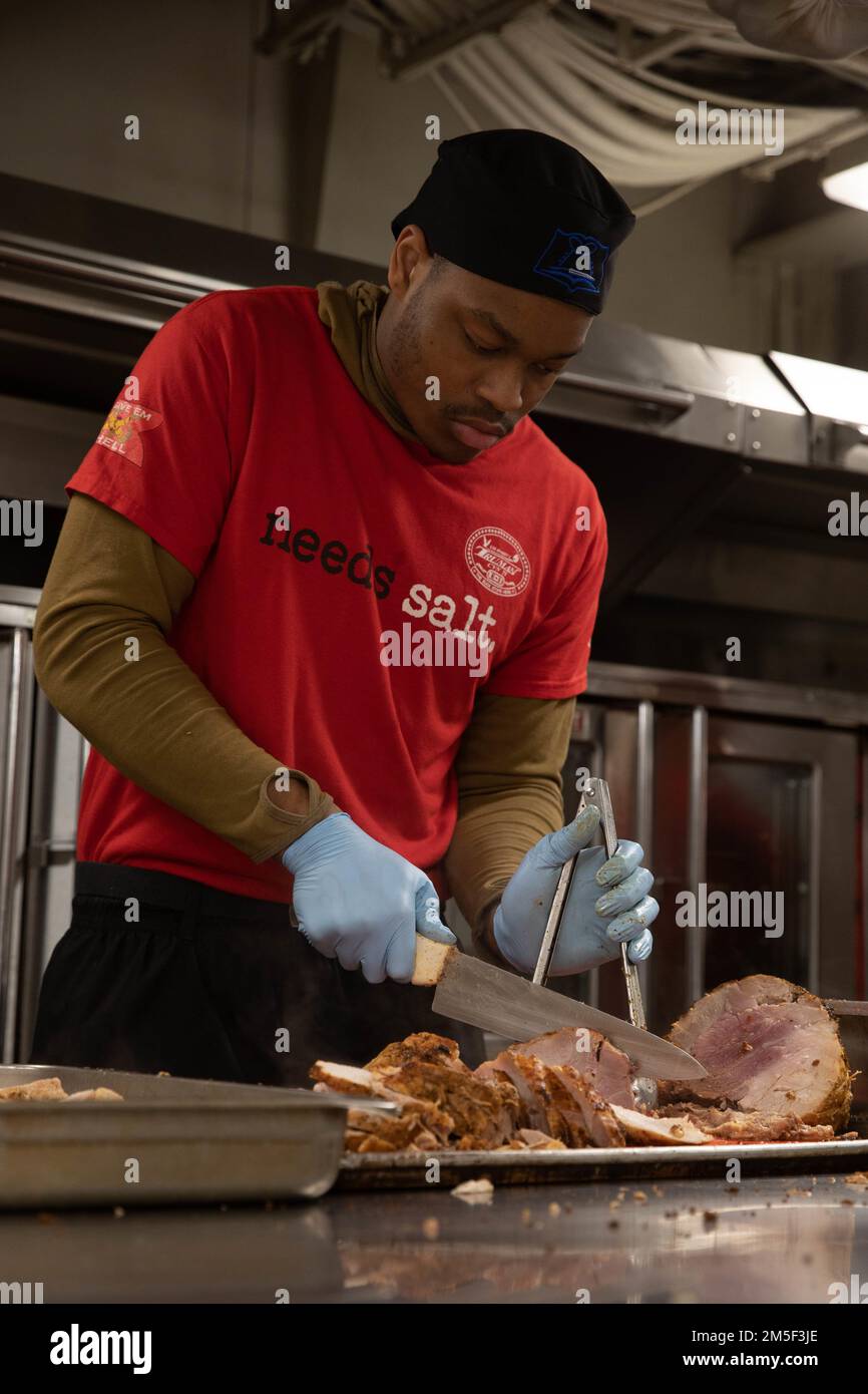 220310-N-QI593-1309 IONIAN SEA (Mar. 10, 2022) Culinary Specialist Kam Carson, from Macon, Georgia, slices roasted turkey aboard the Nimitz-class aircraft carrier USS Harry S. Truman (CVN 75), Mar. 10, 2022. The Harry S. Truman Carrier Strike Group is on a scheduled deployment in the U.S. Sixth Fleet area of operations in support of U.S., allied and partner interests in Europe and Africa. Stock Photo