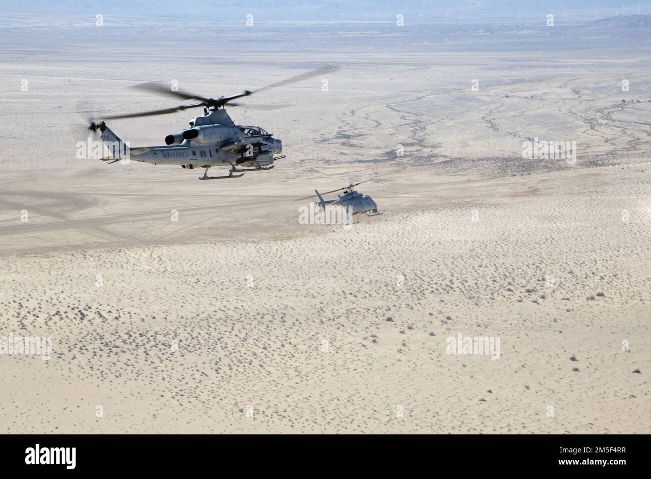 An AH-1Z Viper (left) with Marine Operational and Test Evaluation Squadron 1 (VMX-1), and an MQ-8C Fire Scout unmanned helicopter assigned to Helicopter Sea Combat Squadron 23 (HSC-23), conduct Strike Coordination and Reconnaissance Training near El Centro, California, March 10, 2022. The purpose of this exercise was to provide familiarization and concept development of manned-unmanned teaming. Stock Photo