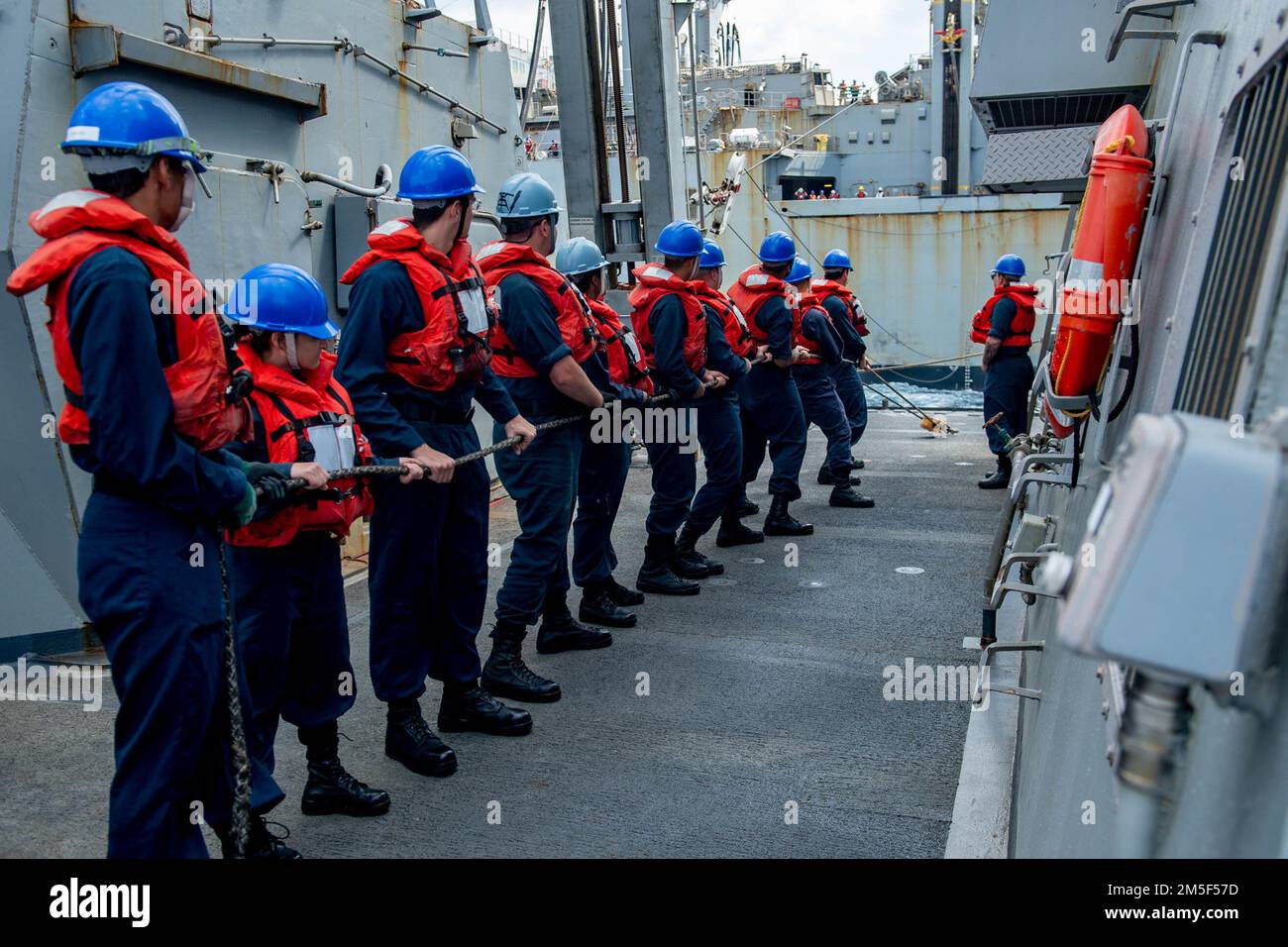 PHILIPPINE SEA (March 10, 2022) Sailors handle lines during a replenishment-at-sea with the Military Sealift Command dry cargo and ammunition ship USNS Alan Shepard (T-AKE 3) aboard the Arleigh Burke-class guided-missile destroyer USS Spruance (DDG 111). Abraham Lincoln Strike Group is on a scheduled deployment in the U.S. 7th Fleet area of operations to enhance interoperability through alliances and partnerships while serving as a ready-response force in support of a free and open Indo-Pacific region. Stock Photo