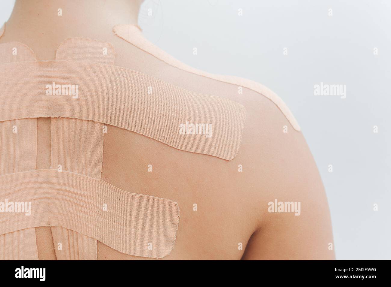 Therapy with kinesio tex tape. Woman with kinesiology tape on back and  shoulder. Isolated on white background Stock Photo - Alamy