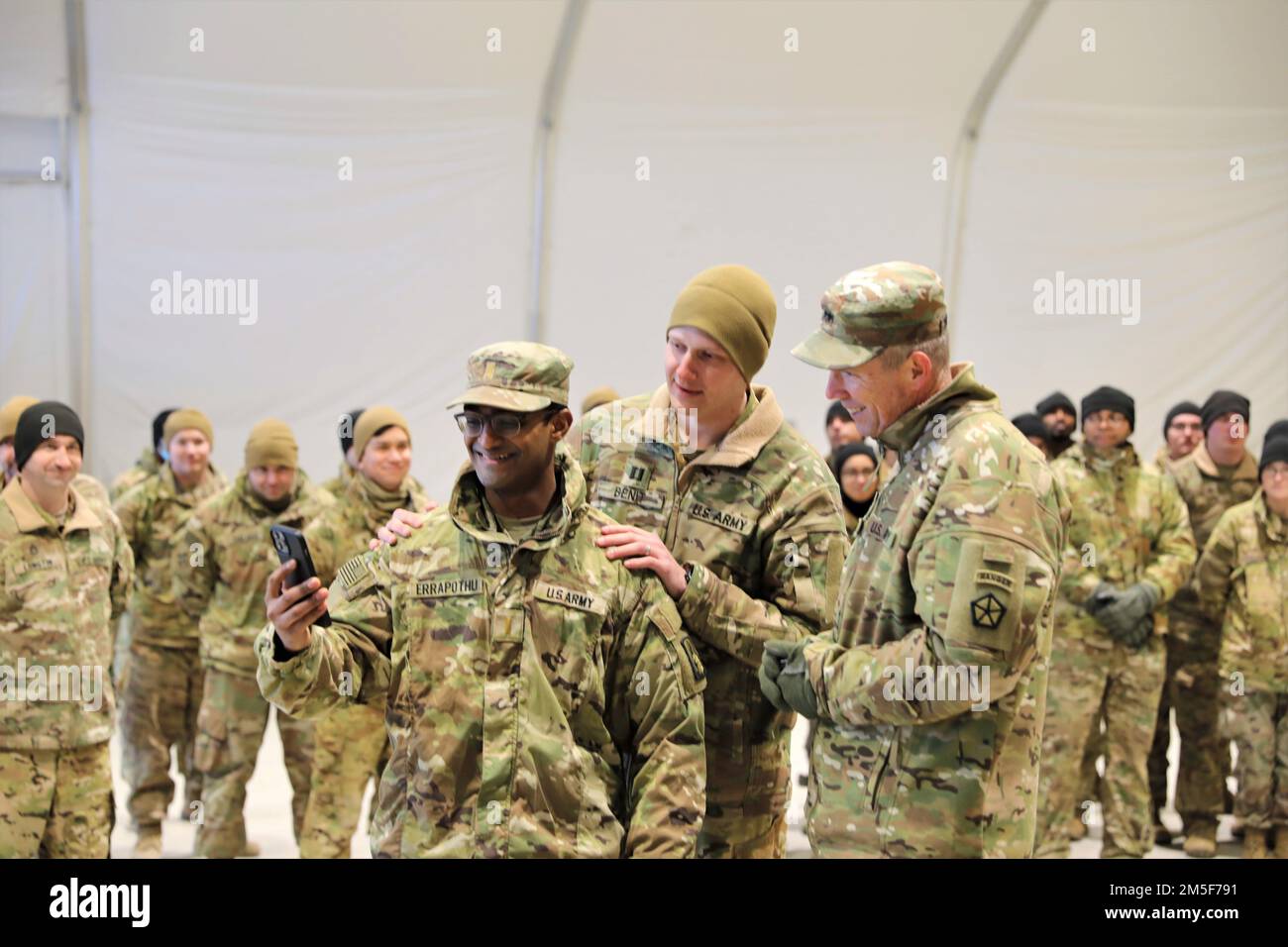 Maj. Gen. Jeffery Broadwater, deputy commanding general, V Corps, spoke with 2nd Lt. Akil Errapothu, ordnance officer, Headquarters and Headquarters Company, 1-3rd Attack Battalion prior to presenting Errapothu with a coin during a visit to Lielvārde Air Base, March 10, 2022. Capt. Dylan Benit (center), commander, Headquarters and Headquarters Company, 1-3rd Attack Battalion, spoke to Errapothu’s wife on the phone about his performance during exercise Saber Strike 22. Broadwater met with the Soldiers of the 1-3rd Attack Battalion and recognized four members of the unit for their performance. Stock Photo