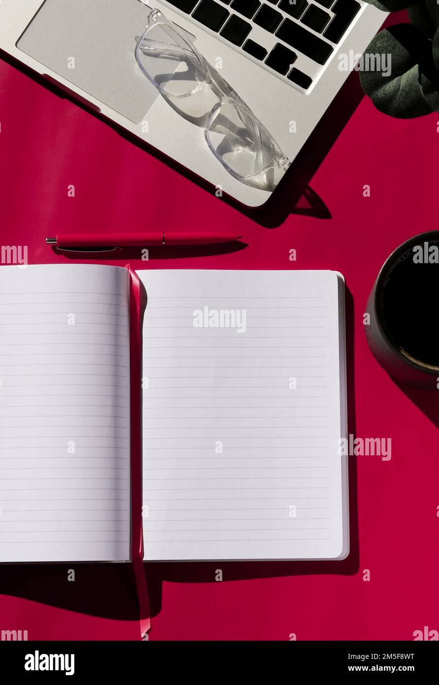 flat lay composition of empty notebook, coffee, computer and glasses on magenta background  Stock Photo
