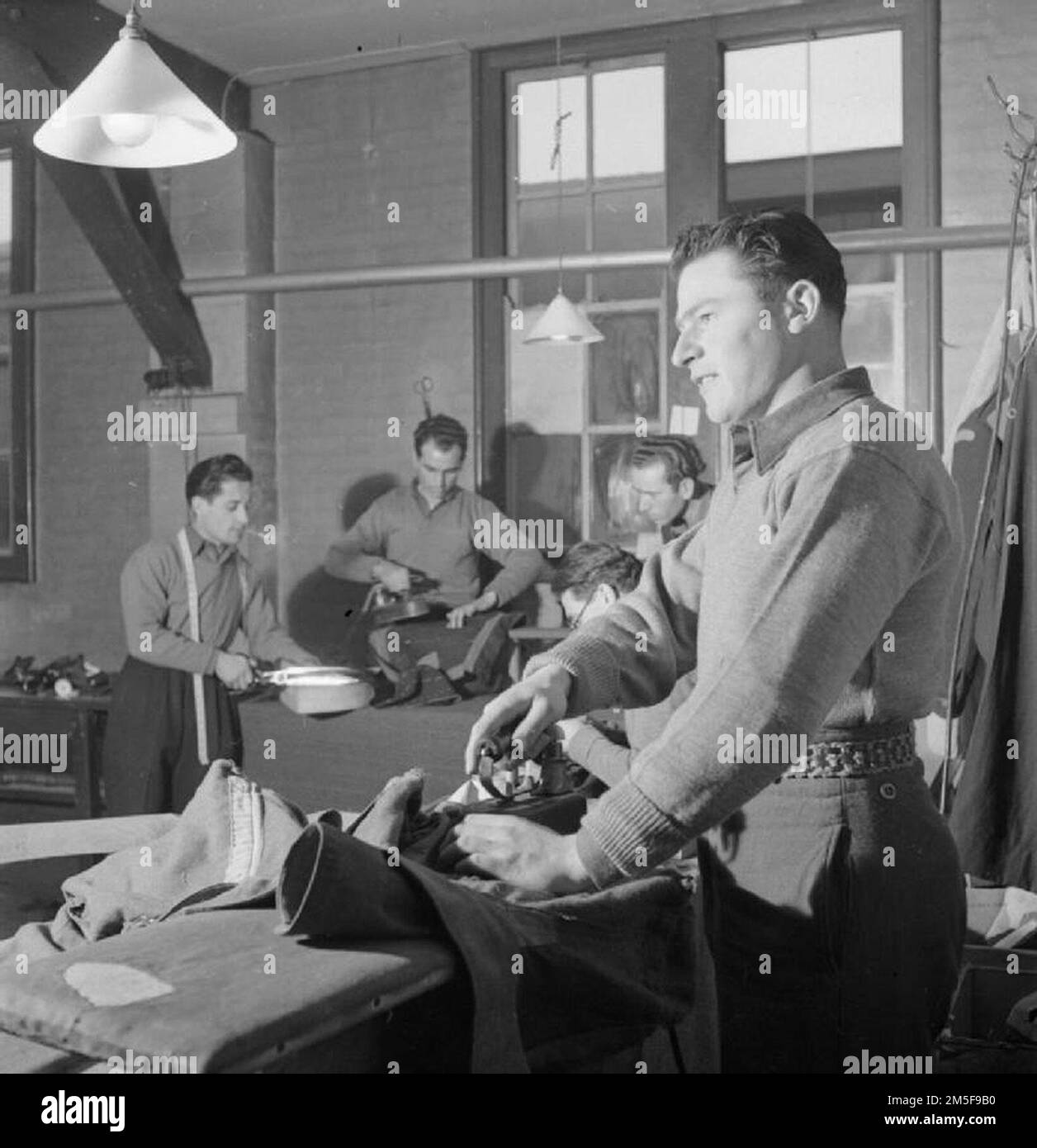 Italian Prisoners of War at work in the tailor's shop of the N.144 workers camp near London.  They are: Vicenzo Romano, Mario Perderzani, Pietro Viviano, Domenico Amorizzo and Salvatore Calicchio. Stock Photo