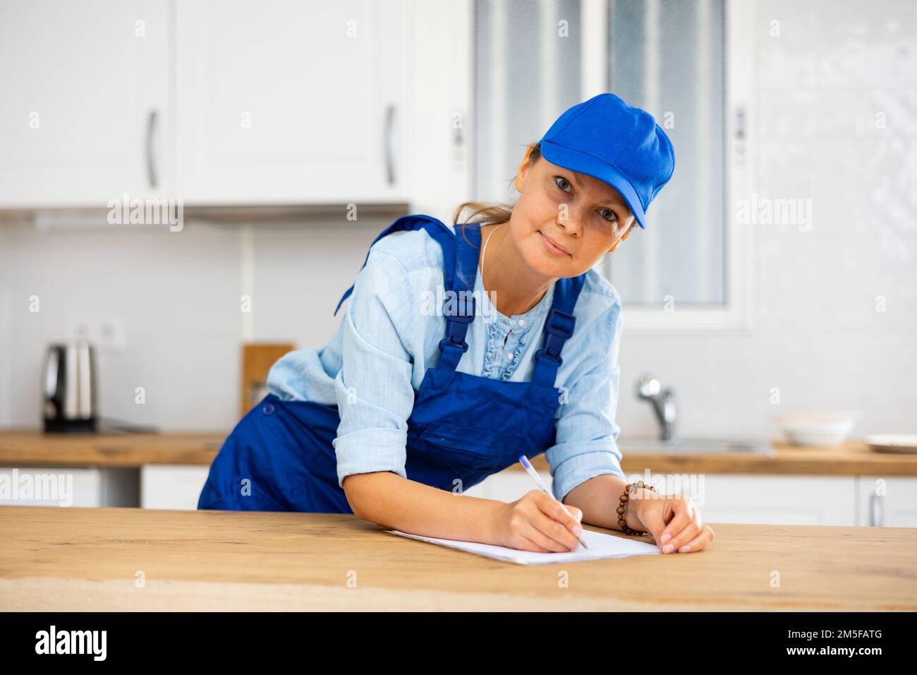 Woman house cleaner making notes in kitchen Stock Photo