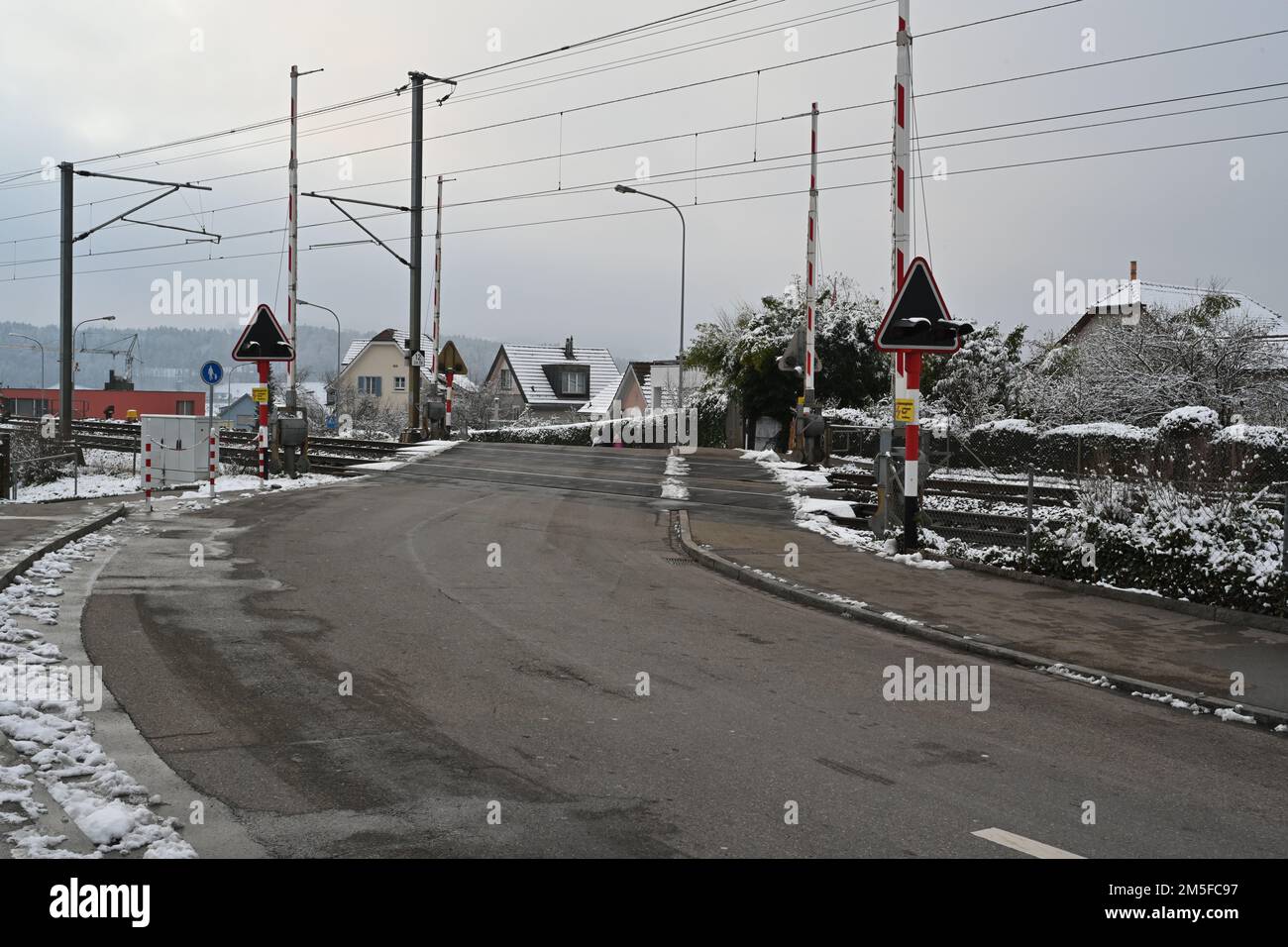 Railway crossing in village Urdorf in winter, captured  with open barriers. Stock Photo