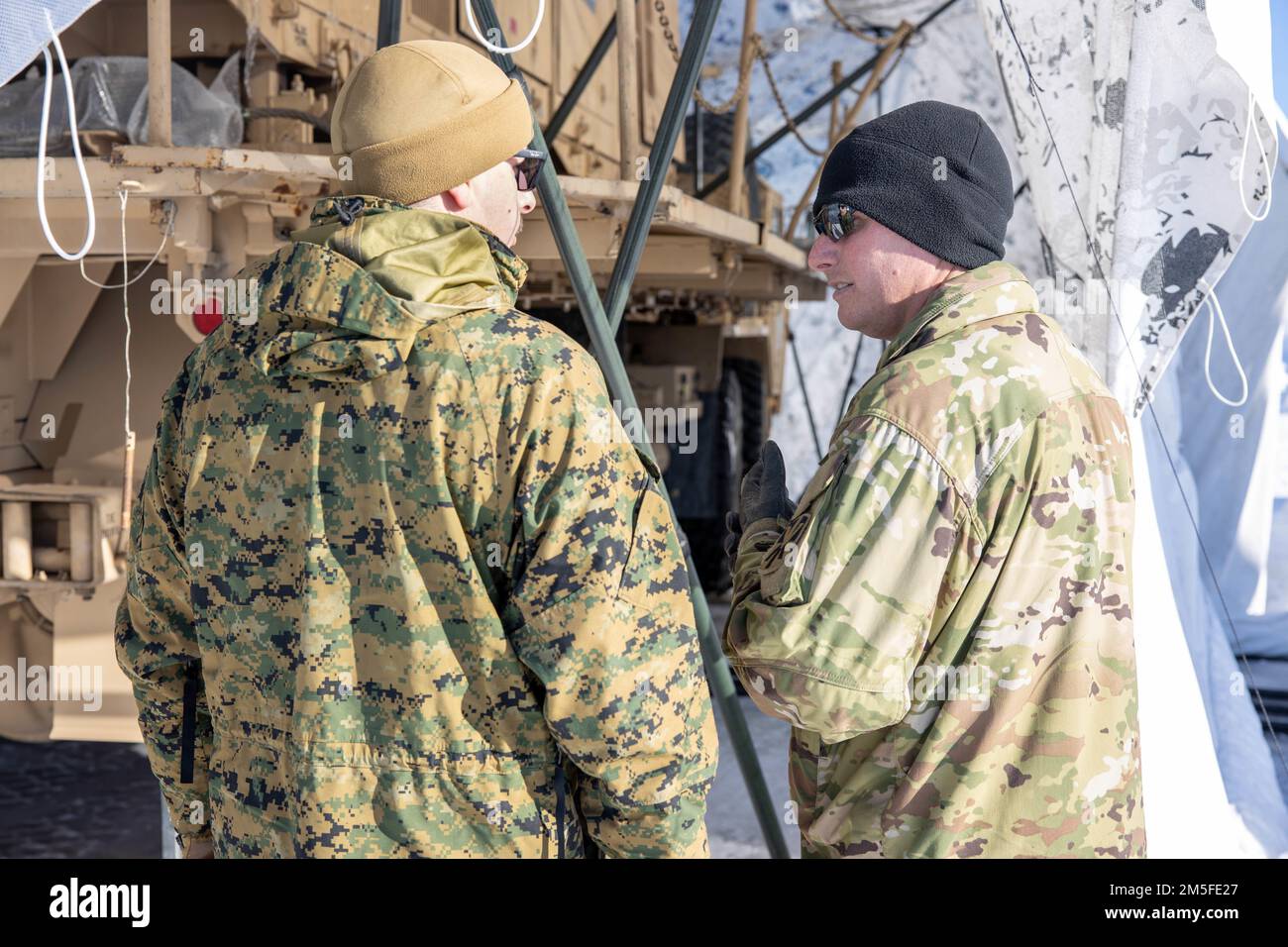U.S. Navy Hospital Corpsman 2nd Class Giuseppe Anile, 2nd Landing Support Battalion, and Sergeant 1st Class Robert Dingle, a Patriot master gunner with 5th Battalion, 52nd Air Defense Artillery Regiment, discuss safety and health measures for Exercise ARCTIC EDGE 2022, at Mullins Point on Eielson Air Force Base, Alaska, March 11, 2022. ARCTIC EDGE is a joint exercise designed to demonstrate our ability to rapidly deploy and operate in the Arctic. Stock Photo
