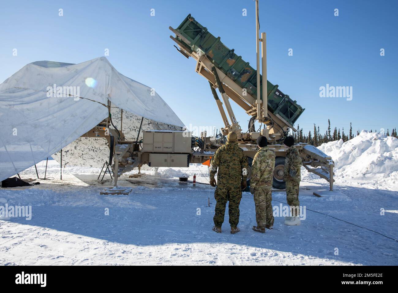 U.S. Navy Hospital Corpsman 2nd Class Giuseppe Anile, 2nd Landing Support Battalion, and U.S. Army Soldiers with 5th Battalion, 52nd Air Defense Artillery Regiment, discuss safety measures regarding the use of the M903 Patriot Launcher during Exercise ARCTIC EDGE 2022, at Mullins Point on Eielson Air Force Base, Alaska, March 11, 2022. ARCTIC EDGE is a joint exercise designed to demonstrate our ability to rapidly deploy and operate in the Arctic. Stock Photo