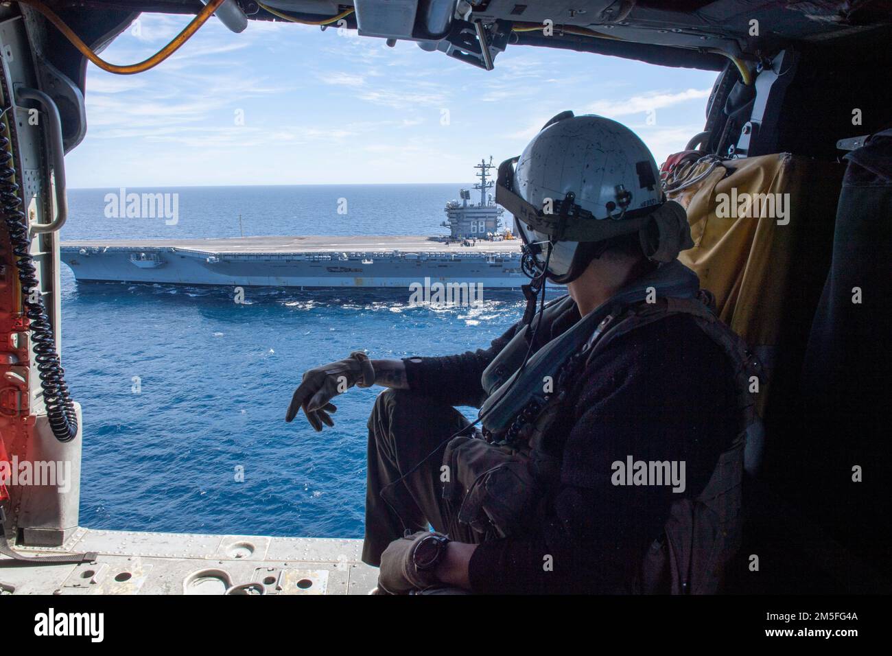 220312-N-KU796-1013 PACIFIC OCEAN (Mar. 12, 2022) A Naval Aircrewman assigned to Helicopter Sea Combat Squadron (HSC) 6, rides in an MH-60S Sea Hawk helicopter. Nimitz is underway conducting routine operations. Stock Photo