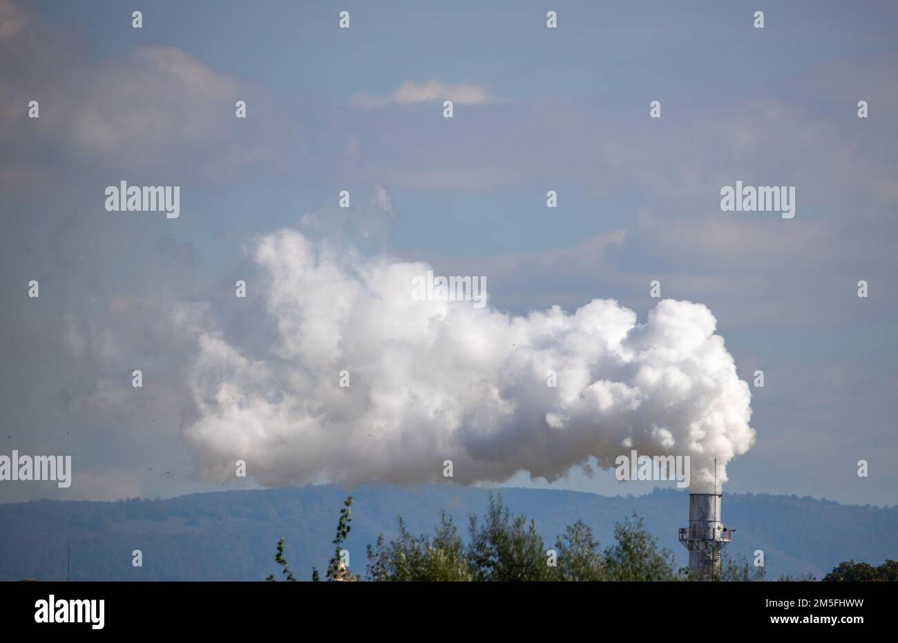 A scenic view of white smoke coming out of an industrial chimney Stock Photo