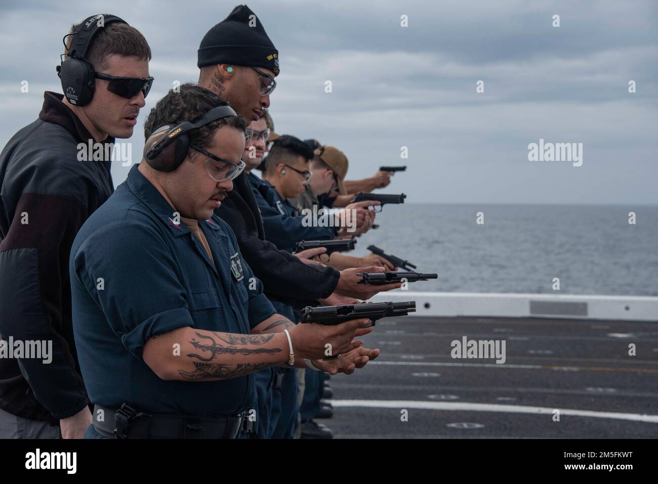 220313-N-XB010-1005 EAST CHINA SEA (March 13, 2022) Sailors assigned to USS New Orleans (LPD 18) fire and reload 9mm handguns during a gun shoot on the flight deck. New Orleans, part of the America Amphibious Ready Group, along with the 31st Marine Expeditionary Unit, is operating in the U.S. 7th Fleet area of responsibility to enhance interoperability with allies and partners and serve as a ready response force to defend peace and stability in the Indo-Pacific region. Stock Photo