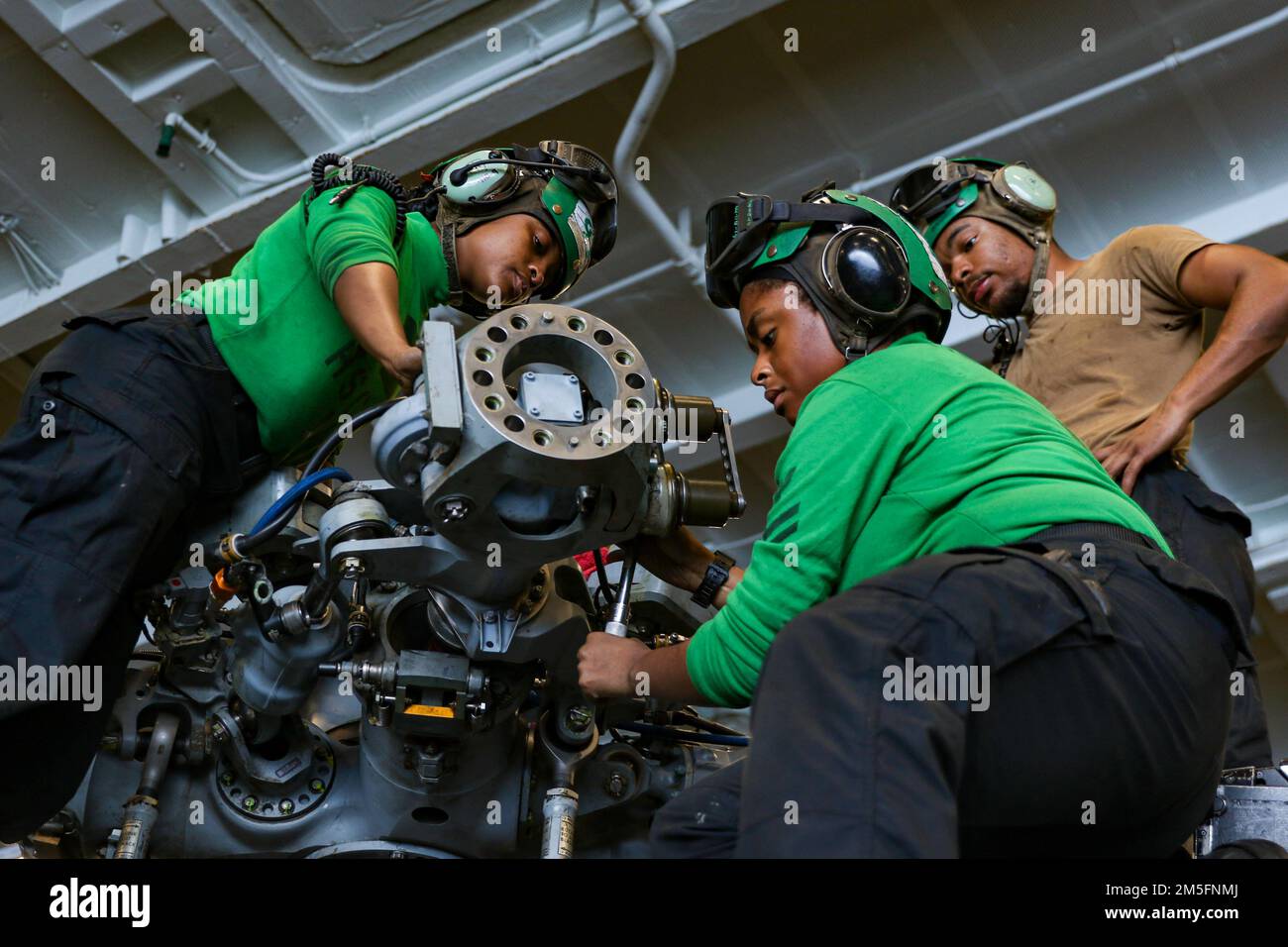 PHILIPPINE SEA (March 15, 2022) Sailors conduct maintenance on the spindle and hinge assembly of an MH-60S Sea Hawk helicopter, assigned to the “Chargers” of Helicopter Sea Combat Squadron (HSC) 14, in the hangar bay aboard the Nimitz-class aircraft carrier USS Abraham Lincoln (CVN 72). Abraham Lincoln Strike Group is on a scheduled deployment in the U.S. 7th Fleet area of operations to enhance interoperability through alliances and partnerships while serving as a ready-response force in support of a free and open Indo-Pacific region. Stock Photo