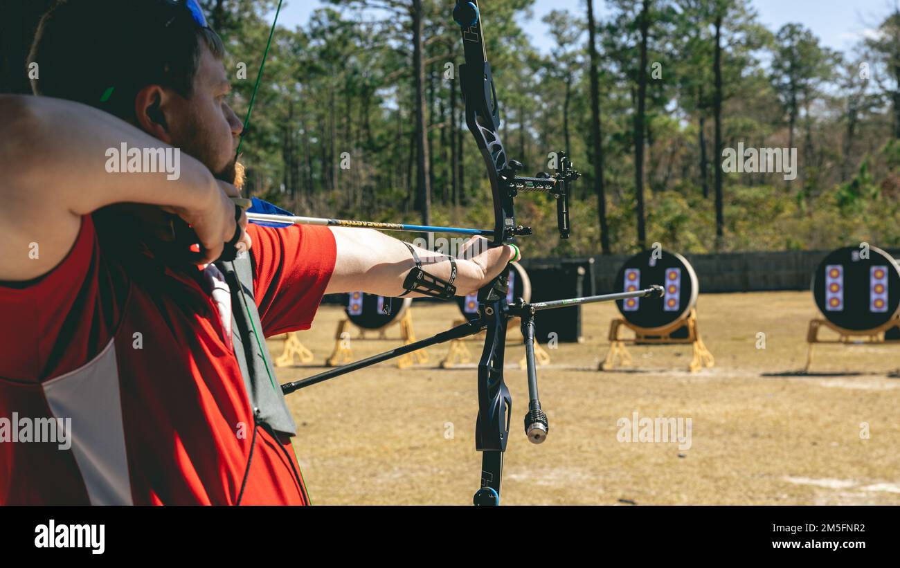 U.S. Marine Corps Ret. Lance Cpl. Christopher Clark, a recovering service member and athlete with Wounded Warrior Battalion East prepares to shoot during the 2022 East Coast Marine Corps Trials archery competition on Marine Corps Base Camp Lejeune, North Carolina, March 14, 2022. The Marine Corps Trials is an annual adaptive sports competition that promotes a competitive warrior spirit, builds camaraderie and provides a venue to select participants for the 2022 DoD Warrior Games. Stock Photo