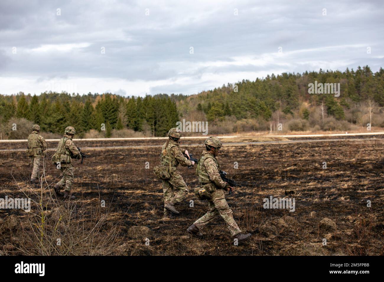 A squad of British Army Officer Cadets with the Royal Military Academy Sandhurst begin a tactical live fire exercise at U.S. 7th Army Training Command's Grafenwoehr Training Area, Grafenwoehr, Germany, March 14, 2022. Stock Photo