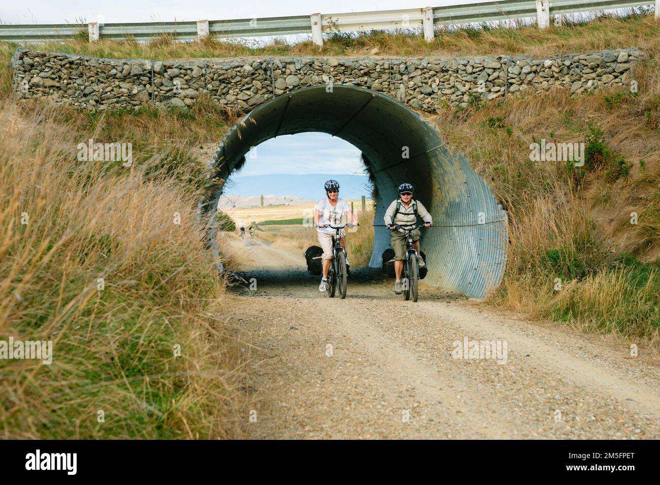 Otago New Zealand - March 1 2010; cyclists passing through tunnel under bridge on Central Otago Rail Trail Stock Photo