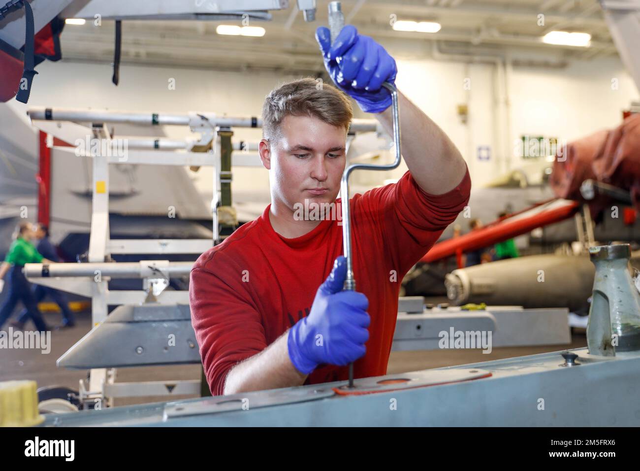 PHILIPPINE SEA (March 15, 2022) Aviation Ordnanceman Airman Cole Giambrone, from Modesto, Calif., assigned to the “Black Aces” of Strike Fighter Squadron (VFA) 41, conducts maintenance on an F/A-18F Super Hornet pylon in the hangar bay aboard the Nimitz-class aircraft carrier USS Abraham Lincoln (CVN 72). Abraham Lincoln Strike Group is on a scheduled deployment in the U.S. 7th Fleet area of operations to enhance interoperability through alliances and partnerships while serving as a ready-response force in support of a free and open Indo-Pacific region. Stock Photo