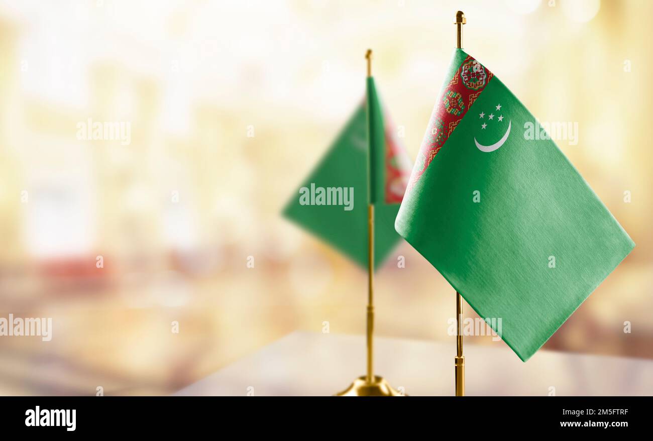 Small flags of the turkmenistan on an abstract blurry background stock