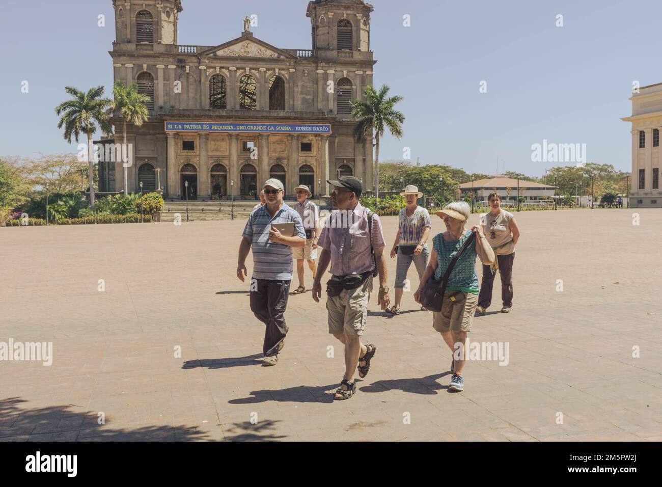 Tourists with a guide walk across the plaza in front of the old  cathedral that was damaged in the 1972 Nicaragua earthquake. Stock Photo