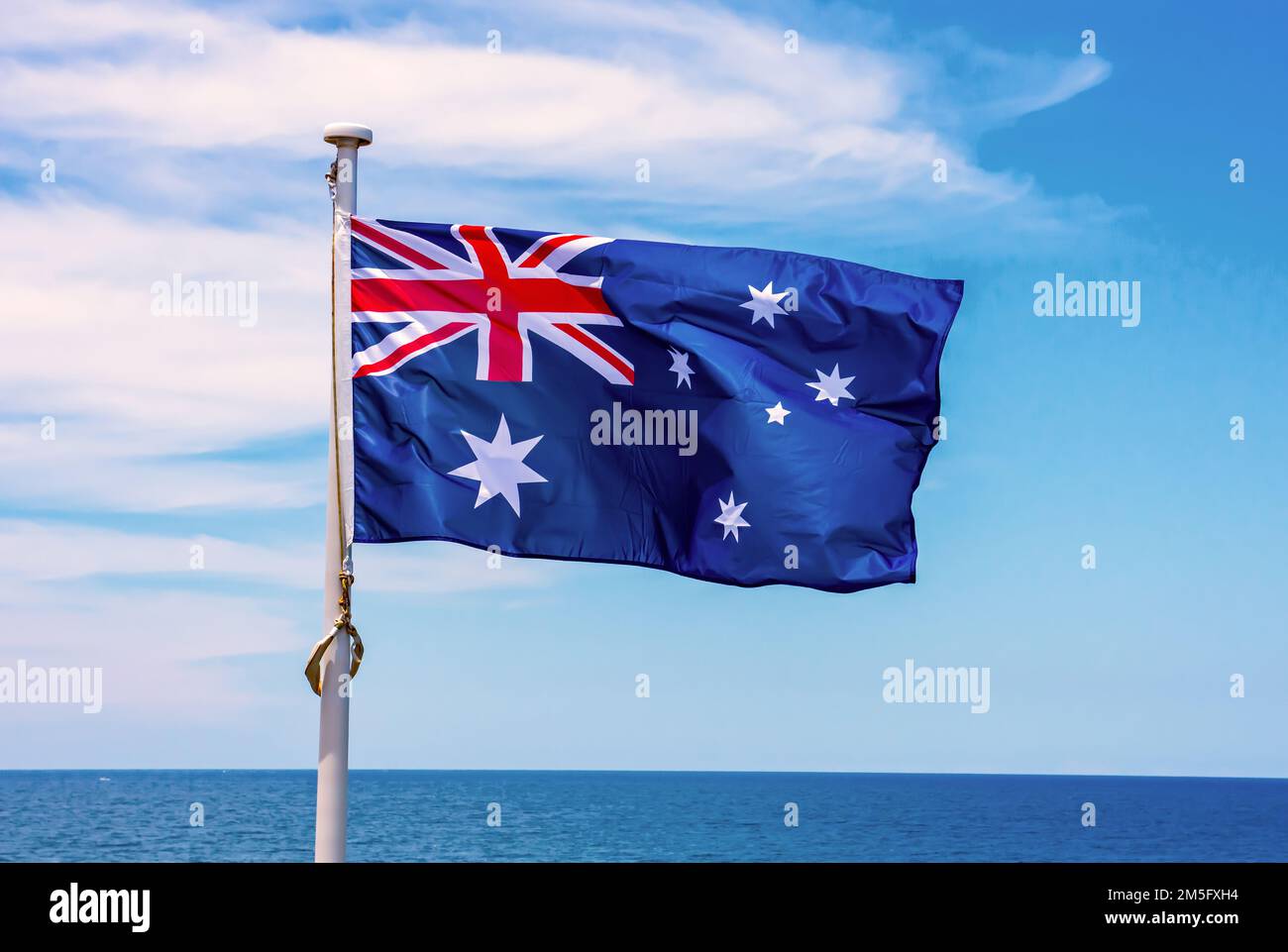 Australian flag flying against a blue ocean Stock Photo