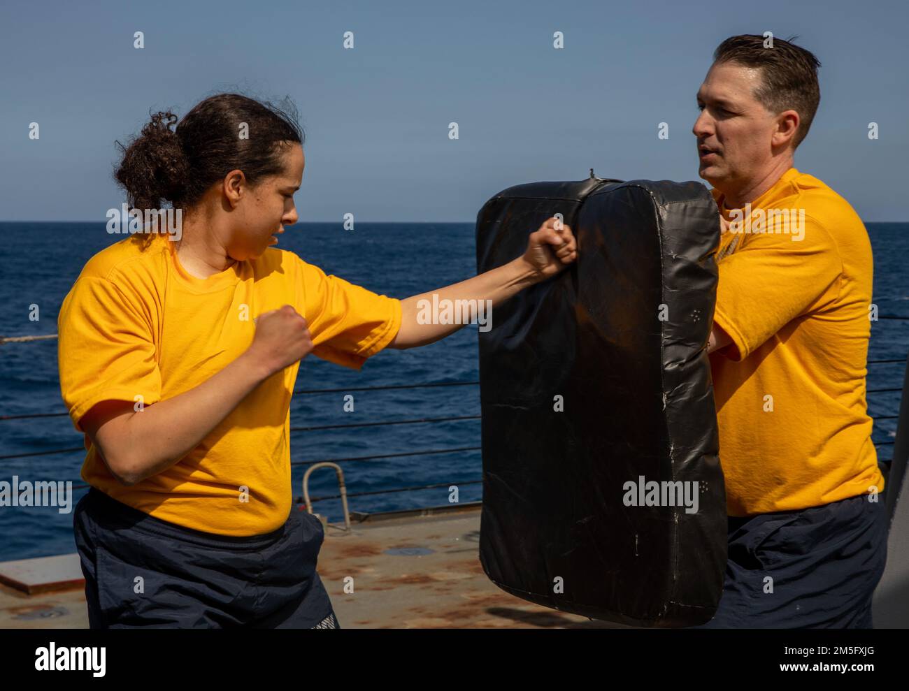 SOUTH CHINA SEA (March 15, 2022) Ensign Catherine Hawkes (left), from Hillsborough, New Jersey, and Lt. j.g. James Hutchison (right), from Huntsville, Alabama, participate in non-lethal weapons training aboard the Arleigh Burke-class guided-missile destroyer USS Ralph Johnson (DDG 114). Ralph Johnson is assigned to Task Force 71/Destroyer Squadron (DESRON) 15, the Navy’s largest forward-deployed DESRON and the U.S. 7th fleet’s principal surface force. Stock Photo