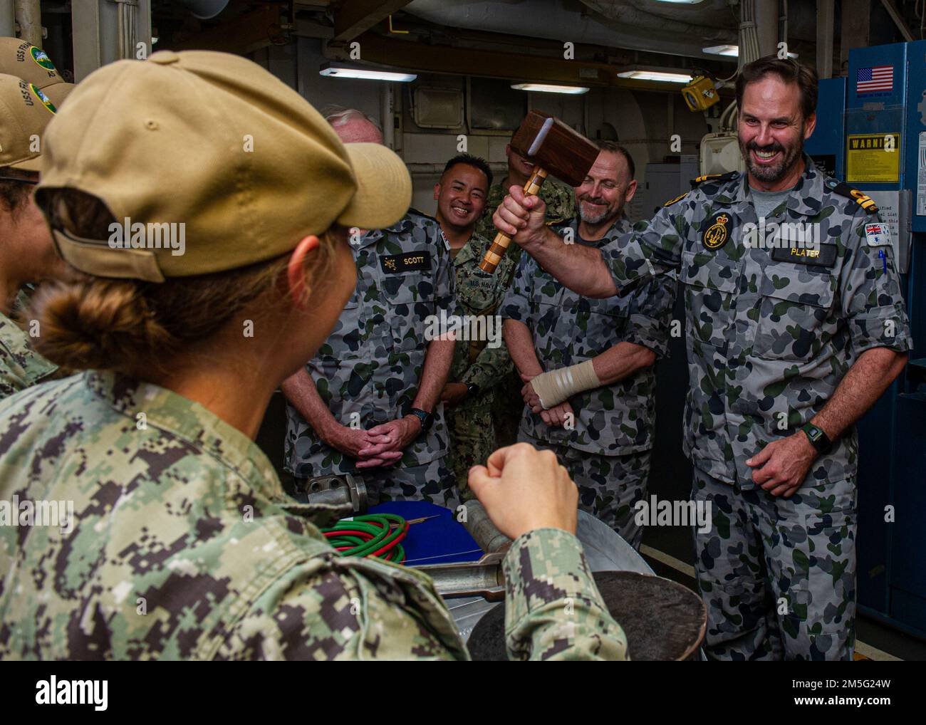 BRISBANE, Australia (March. 16, 2022) U.S. Navy Hull Technician 2nd Class Pamela Hensley, assigned the Emory S. Land-class submarine tender USS Frank Cable (AS 40), explains the capabilities of the carpentry shop onboard the ship to Royal Australian Navy Lt. Rob Plater, assigned to HMAS Moreton, during a tour of Frank Cable, March 16. Frank Cable is currently on patrol conducting expeditionary maintenance and logistics in support of national security in the U.S. 7th Fleet area of operations Stock Photo
