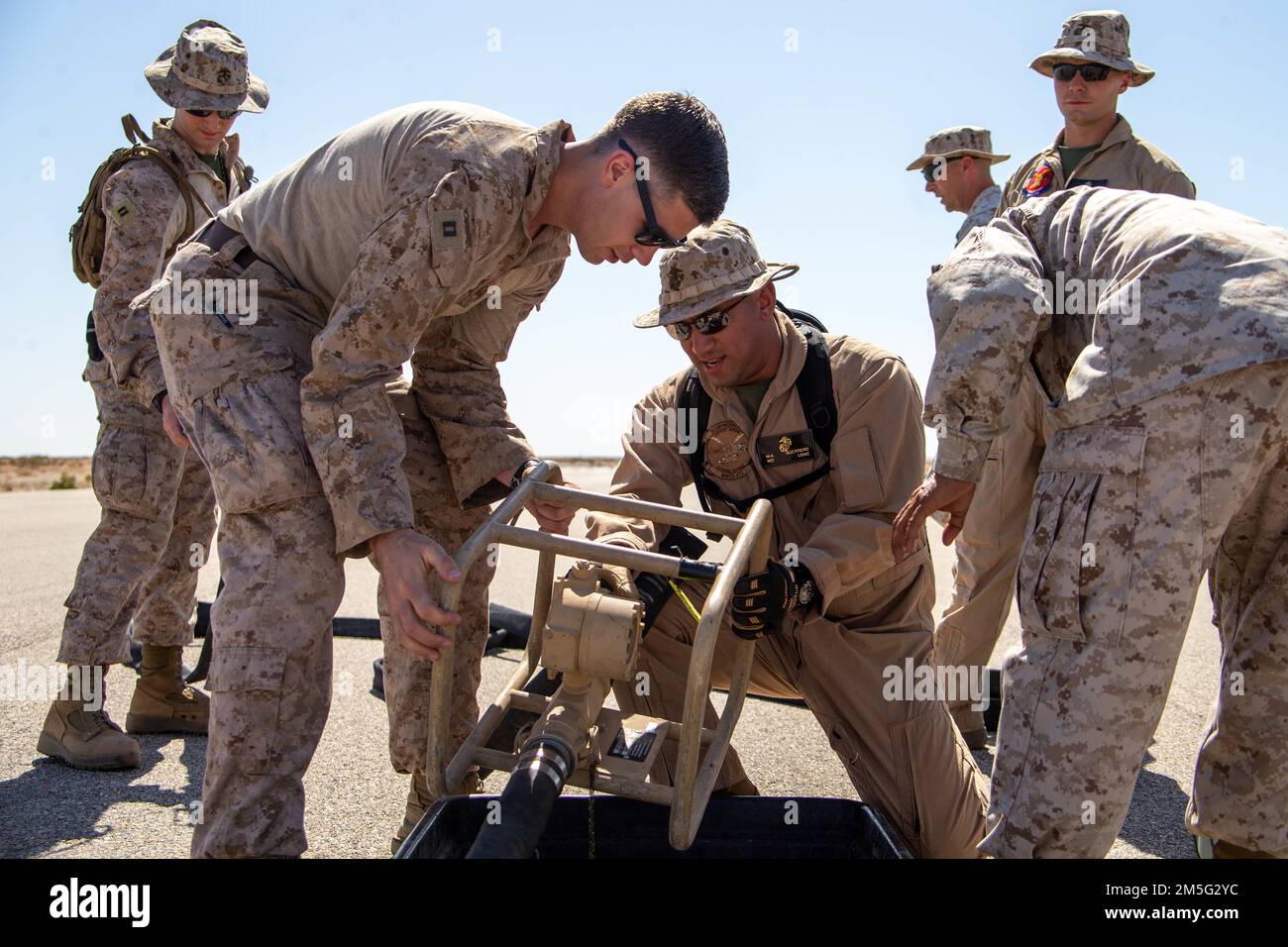 U.S. Marine Corps Capt. Jacob Schiltz, a logistics officer, left, and Warrant Officer Manuel Guerrero, an expeditionary airfield and emergency services officer, assigned to Aviation Ground Support, Marine Aviation Weapons and Tactics Squadron One (MAWTS-1) connect fuel hoses to a fuel meter during a forward arming and refueling point (FARP) practical application, while participating in the Weapons and Tactics Instructor (WTI) course 2-22, at Auxiliary Airfield II, near Yuma, Arizona, March 16, 2022. WTI is a seven-week training event hosted by MAWTS-1, providing standardization advanced tactic Stock Photo
