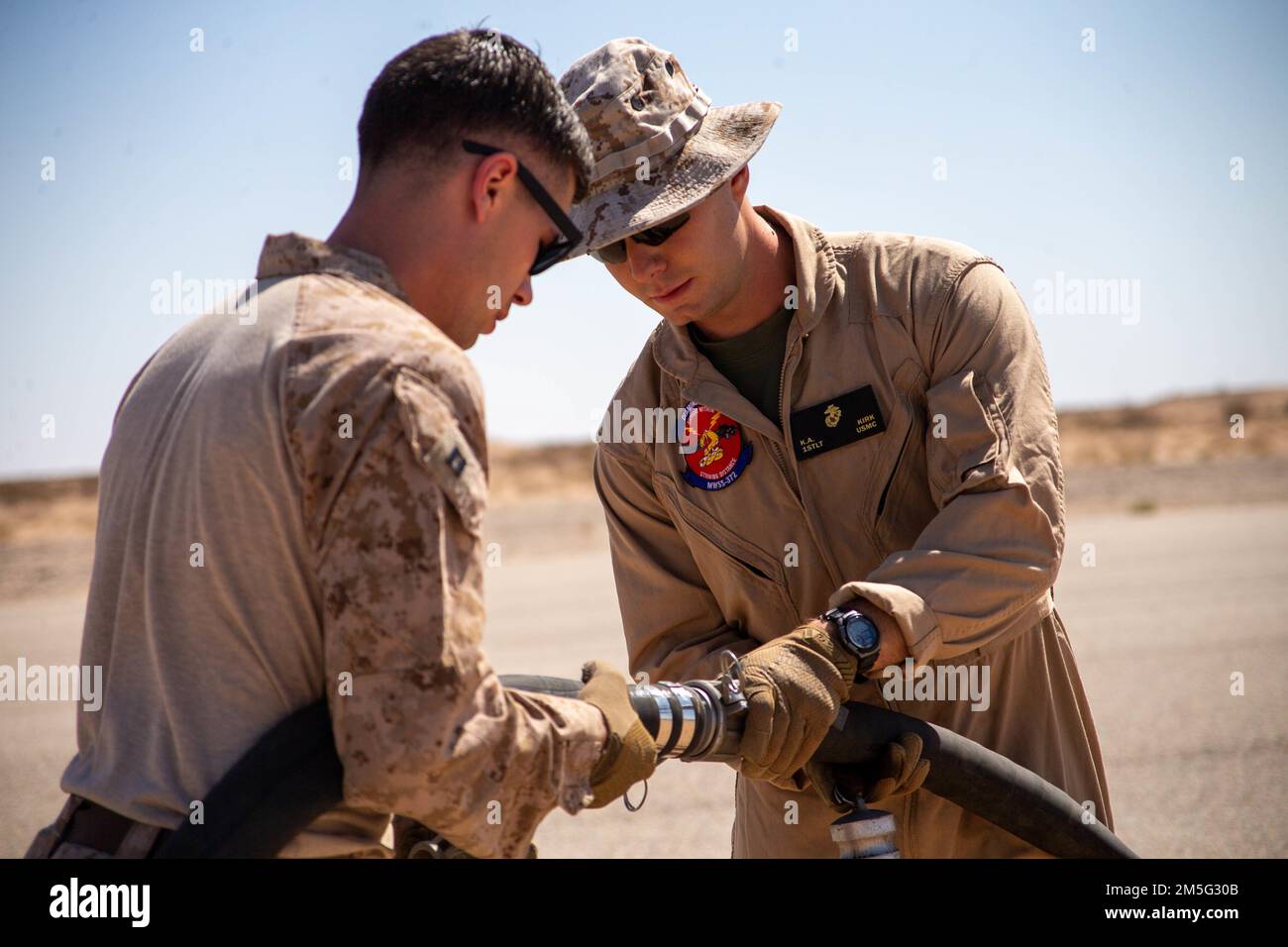 U.S. Marine Corps Capt. Jacob Schiltz, a logistics officer, left, and 1st Lt. Kevin , combat engineer officer, both with Aviation Ground Support, Marine Aviation Weapons and Tactics Squadron One (MAWTS-1), connect fuel hoses during a forward arming and refueling point (FARP) practical application, during Weapons and Tactics Instructor (WTI) course 2-22, at Auxiliary Airfield II, near Yuma, Arizona, March 16, 2022. WTI is a seven-week training event hosted by MAWTS-1, providing standardization advanced tactical training and certification of unit instructor qualifications to support Marine aviat Stock Photo