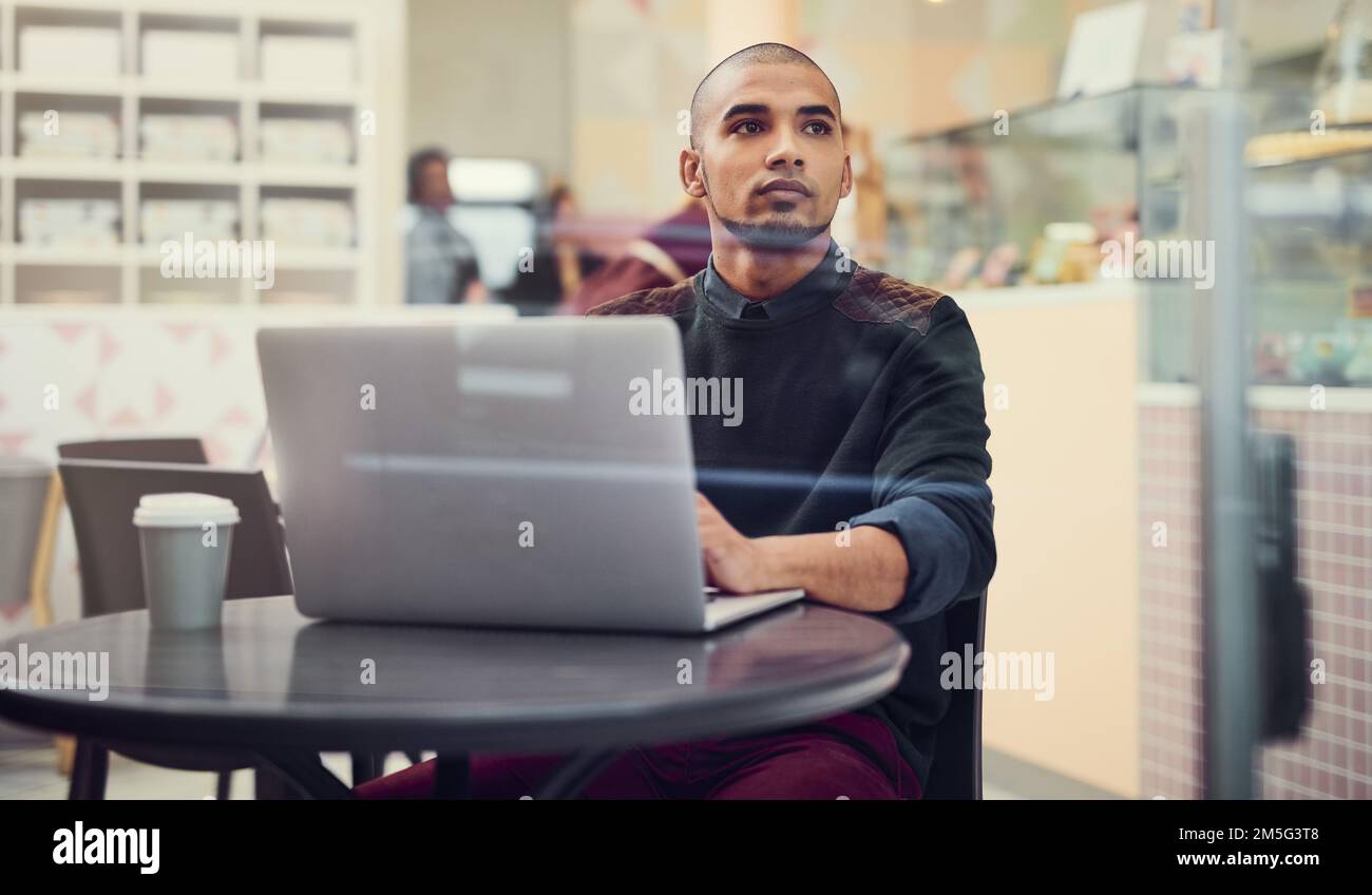 This is where inspiration strikes...a young man using his laptop in a cafe. Stock Photo
