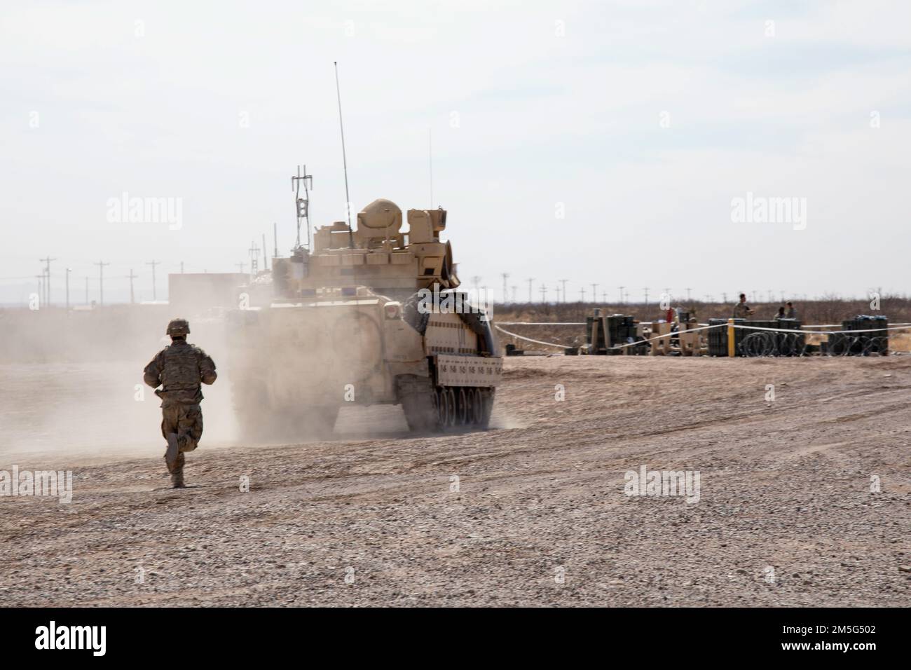 A Soldier from 2nd Armored Brigade Combat Team, 1st Armored Division brings up the rear as he helps escort a Bradley Fighting Vehicle off the gunnery range near Fort Bliss, Texas, on March 16, 2022. 2nd BDE is performing gunnery tables for upcoming training events. Stock Photo
