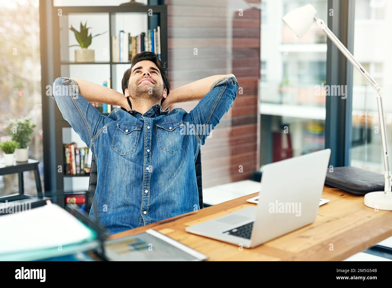 Its been a perfect and productive day. a young businessman leaning back in his chair. Stock Photo