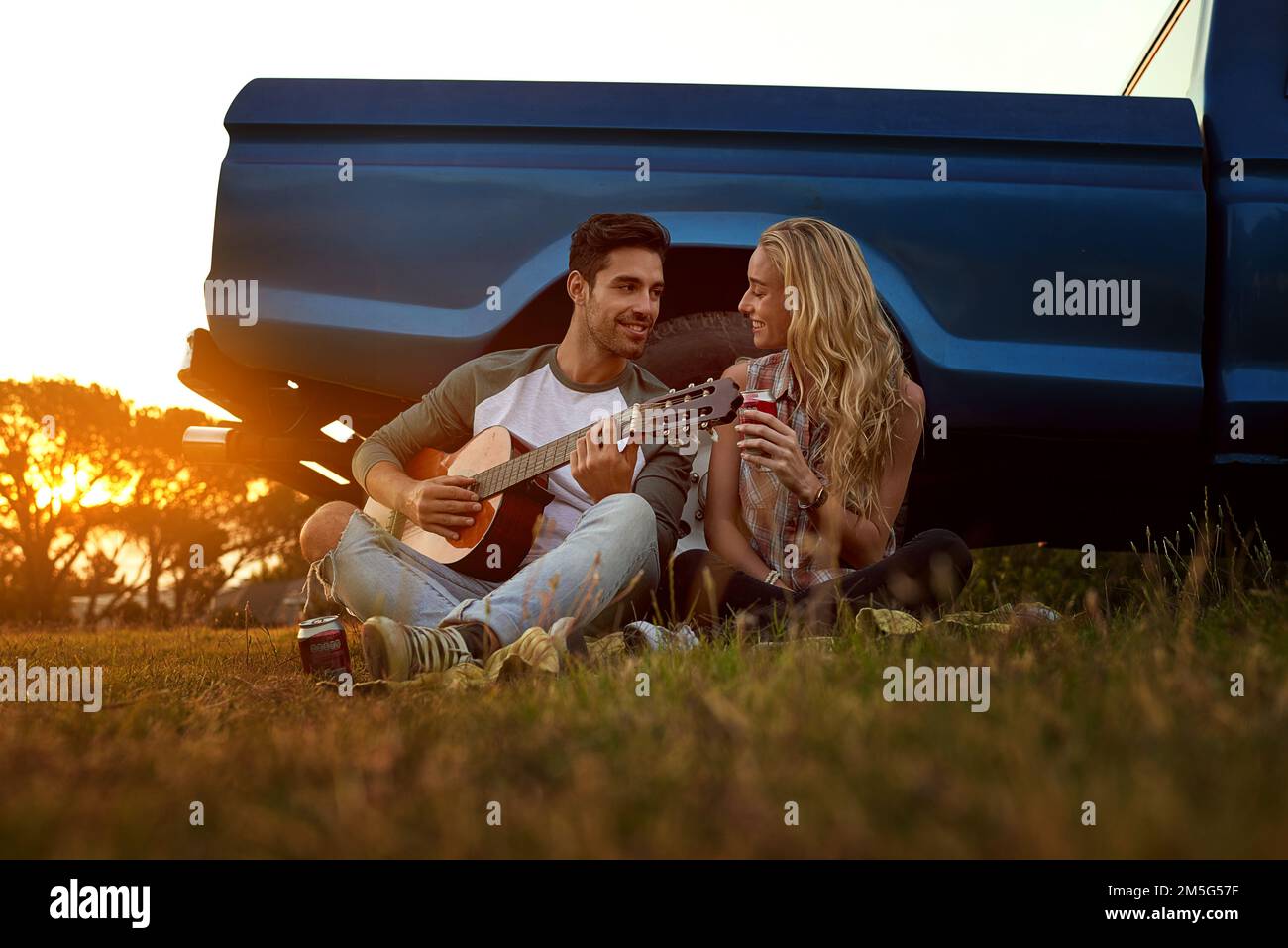Songs of love and romance. a young man playing guitar for his girlfriend on a roadtrip. Stock Photo