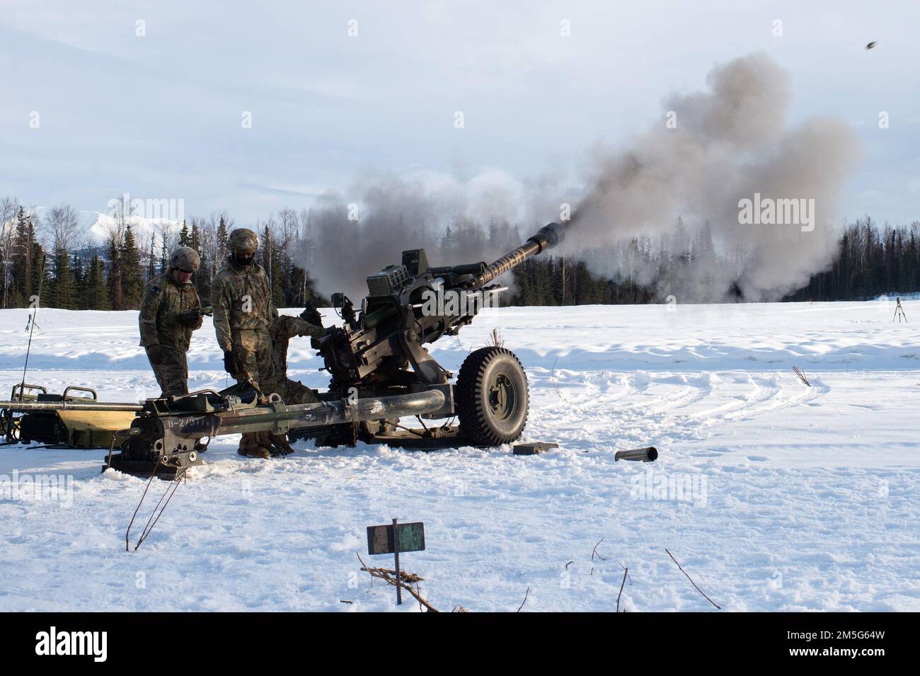 U.S. Army paratroopers assigned to Bravo Battery, 2nd Battalion, 377th Parachute Field Artillery Regiment, 4th Infantry Brigade Combat Team (Airborne), 25th Infantry Division, U.S. Army Alaska, fire the M119 105 mm howitzer during live-fire artillery training at Joint Base Elmendorf-Richardson, Alaska, March 16, 2022. The Soldiers of 4/25 belong to the only American airborne brigade in the Pacific and are trained to execute airborne maneuvers in extreme cold weather and high altitude environments in support of combat, partnership and disaster relief operations. Stock Photo