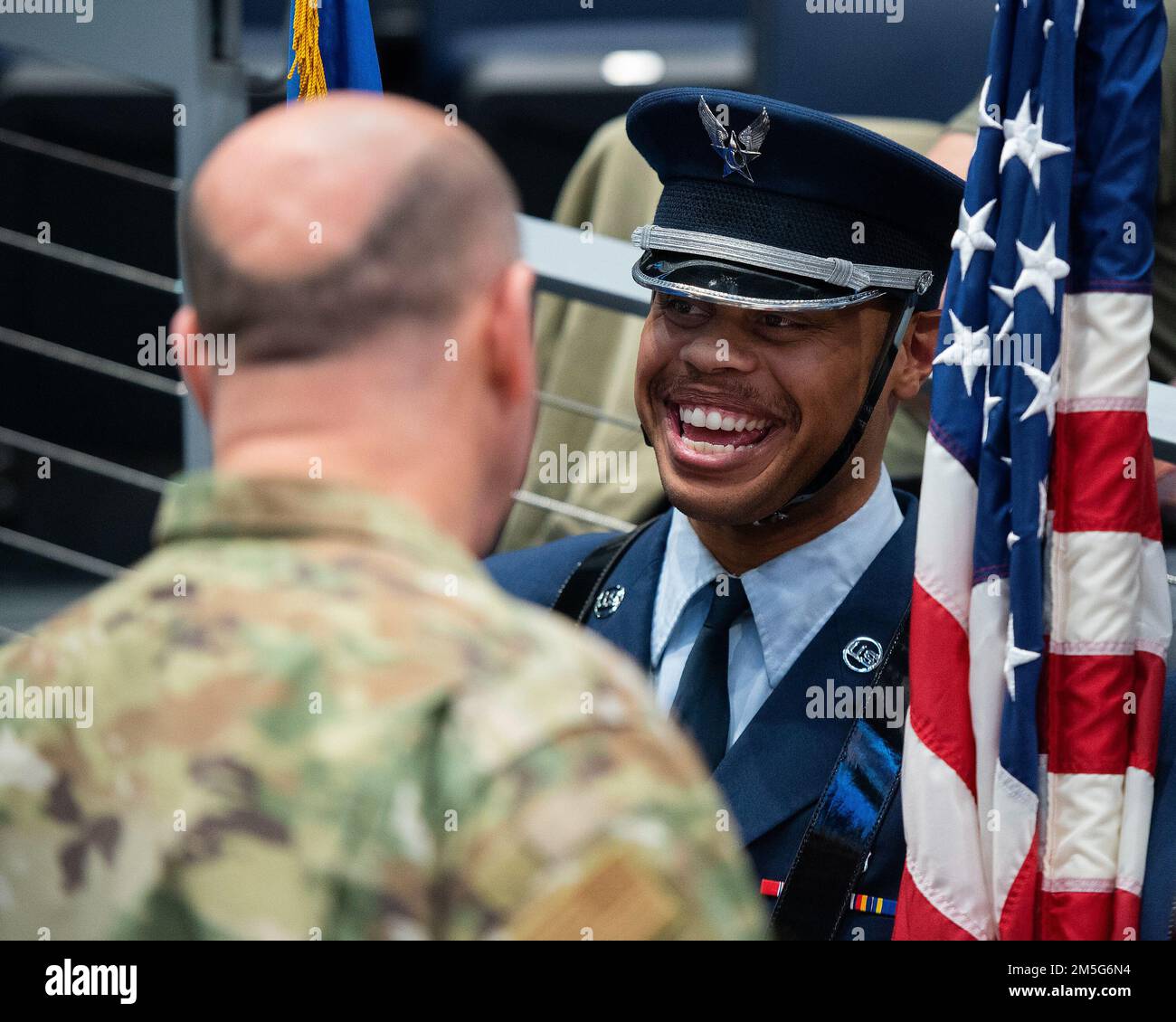 Senior Airman McKinley Gillis, Wright-Patterson Air Force Base guardsman, laughs with Col. Patrick Miller, 88th Air Base Wing and WPAFB commander, on March 16, 2022, prior to the Honor Guard taking part in the opening ceremony of the NCAA men’s basketball tournament First Four game between Wright State and Bryant. The base was also represented by a group of Airmen unfurling a large American flag. Stock Photo