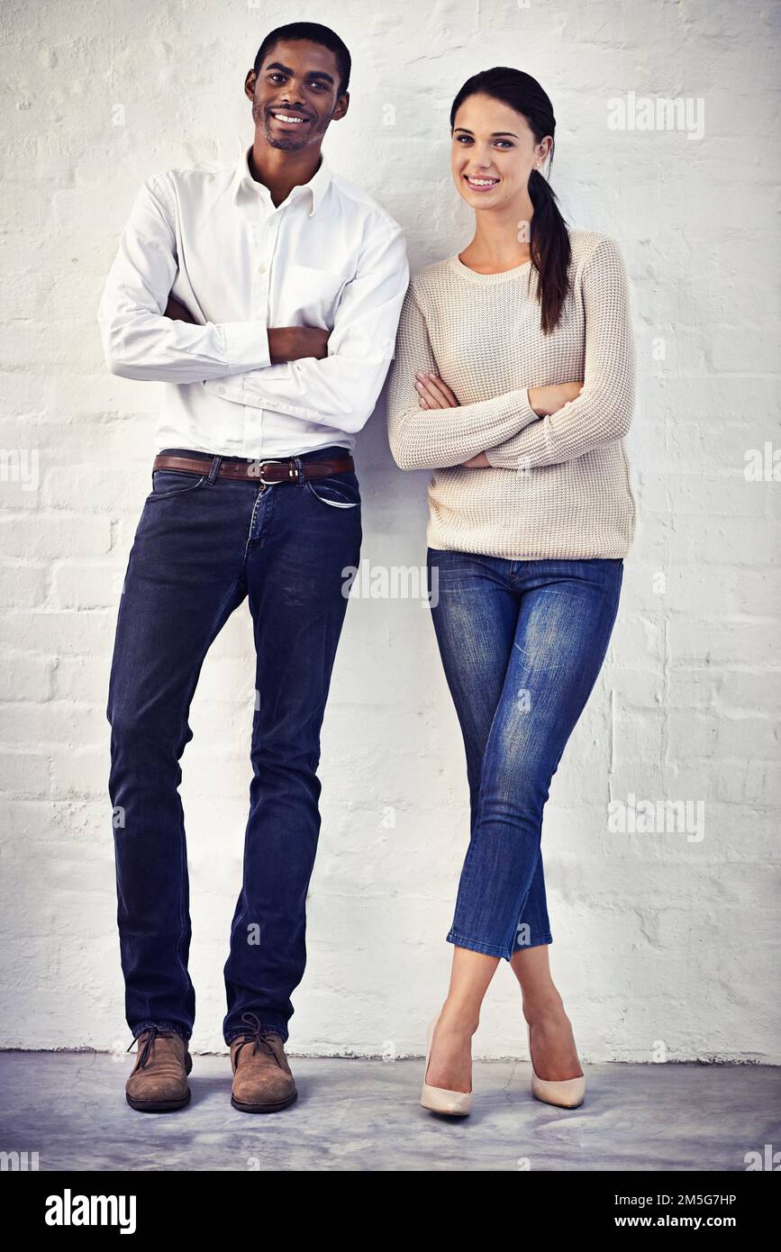 Stylish and we know it. Portrait of a two casually dressed friends standing side by side against a brick wall. Stock Photo