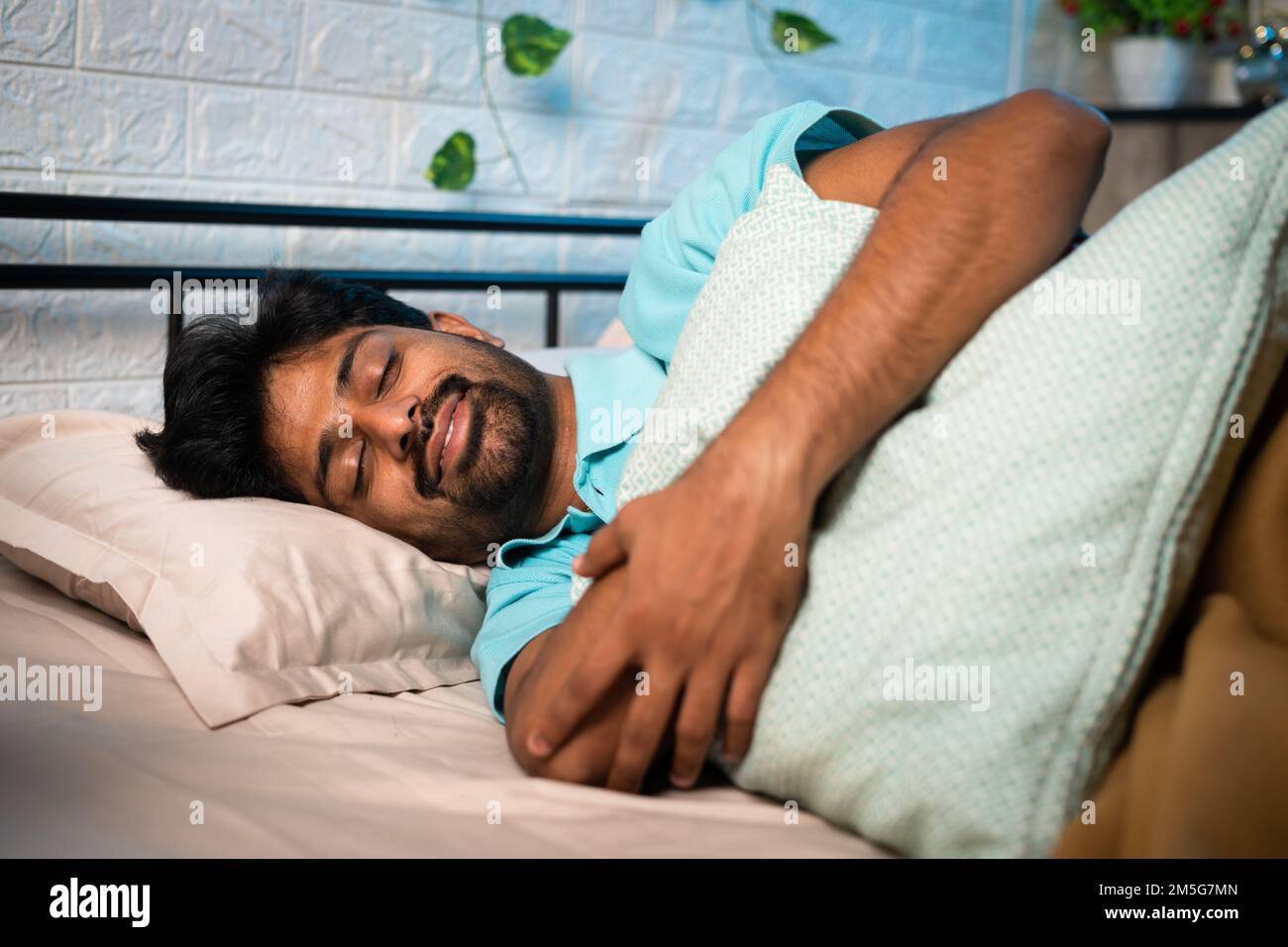 happy young man sleeping comfortably by hugging pillow - concept of