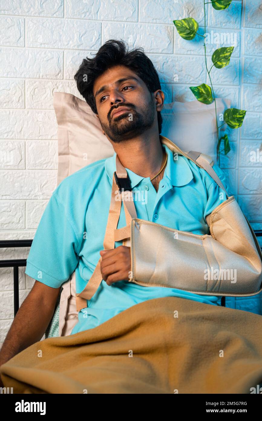 thoughful Young man suffering from broken or injured hand at home