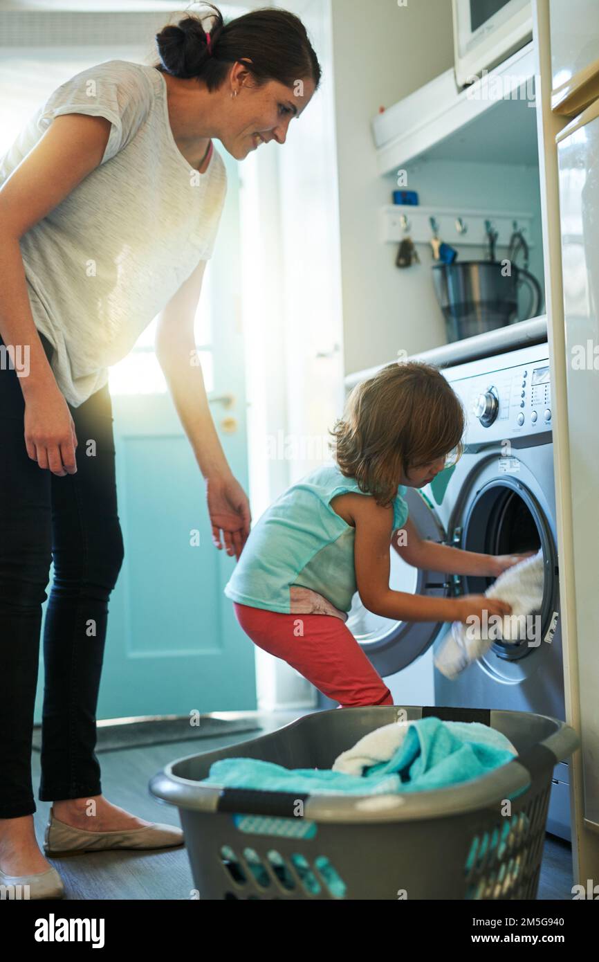 Loading the washing machine. a mother and daughter using a washing