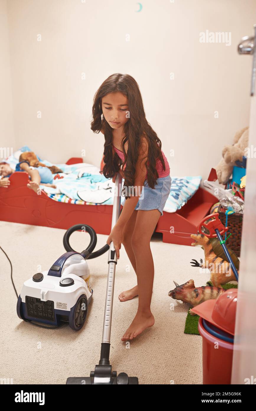Its save to say Im almost done. a focused young little girl using a vacuum cleaner to clean his room at home. Stock Photo