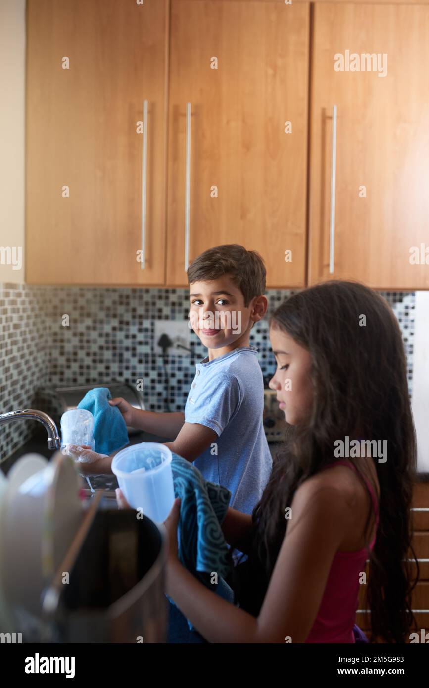Housekeeping is a joint effort. a young brother and sister wash dishes ...