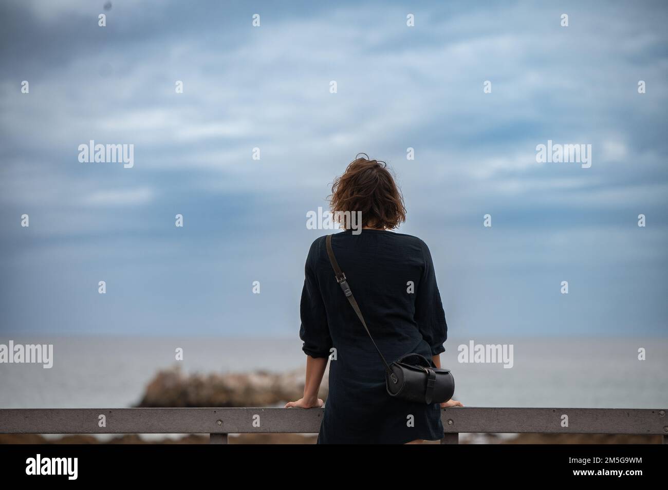 Woman standing and watching the sea Stock Photo - Alamy