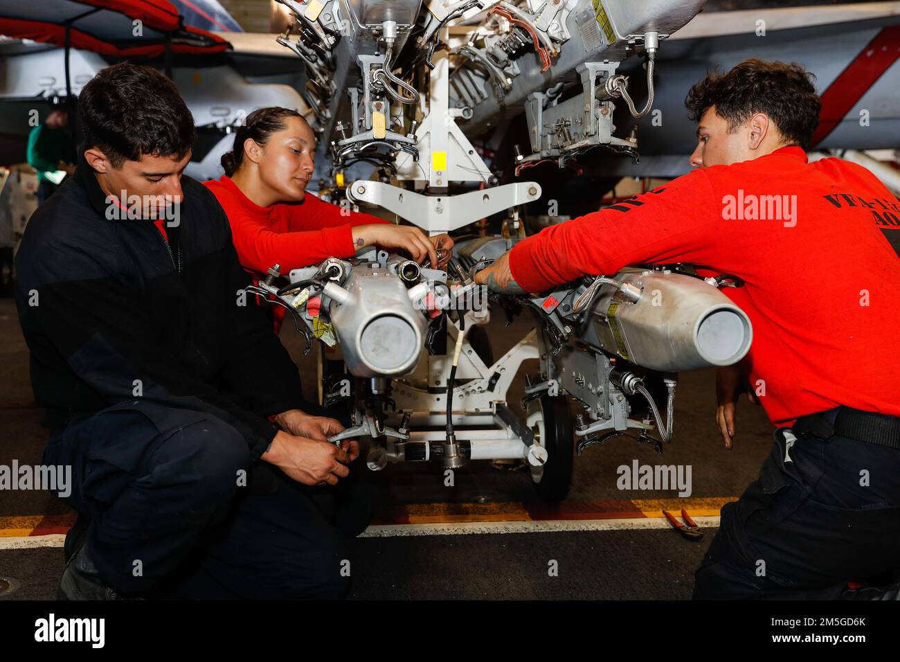 PHILIPPINE SEA (March 17, 2022) Sailors, assigned to the “Vigilantes” of Strike Fighter Squadron (VFA) 151, conduct maintenance on an improved multiple ejection rack (IMER) in the hangar bay aboard the Nimitz-class aircraft carrier USS Abraham Lincoln (CVN 72). Abraham Lincoln Strike Group is on a scheduled deployment in the U.S. 7th Fleet area of operations to enhance interoperability through alliances and partnerships while serving as a ready-response force in support of a free and open Indo-Pacific region. Stock Photo