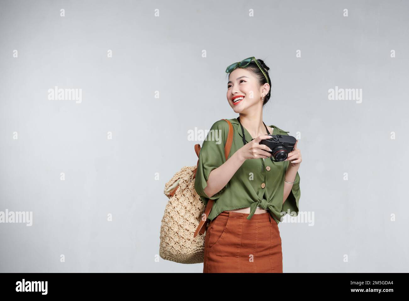Image of joyful woman holding retro camera and smiling isolated over gray background Stock Photo