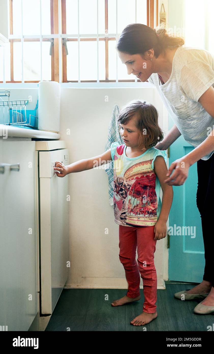 Teaching her how to operate the dishwasher. a mother and daughter busy