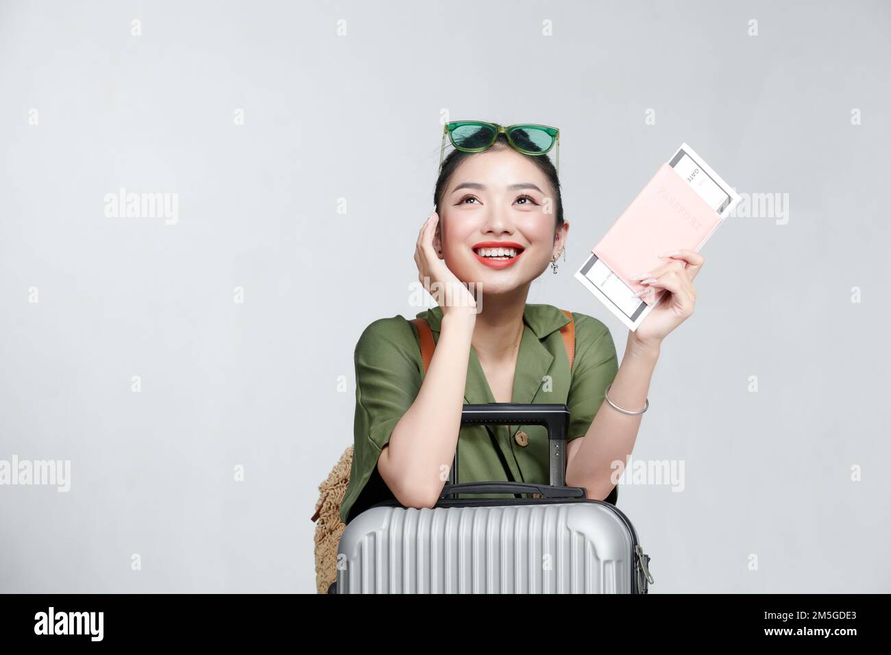 Portrait of a cheerful beautiful young woman with a suitcase, holding mobile phone Stock Photo