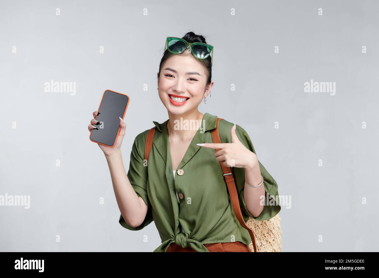 Asian pretty woman tourist preparing for travel showing smartphone screen Stock Photo