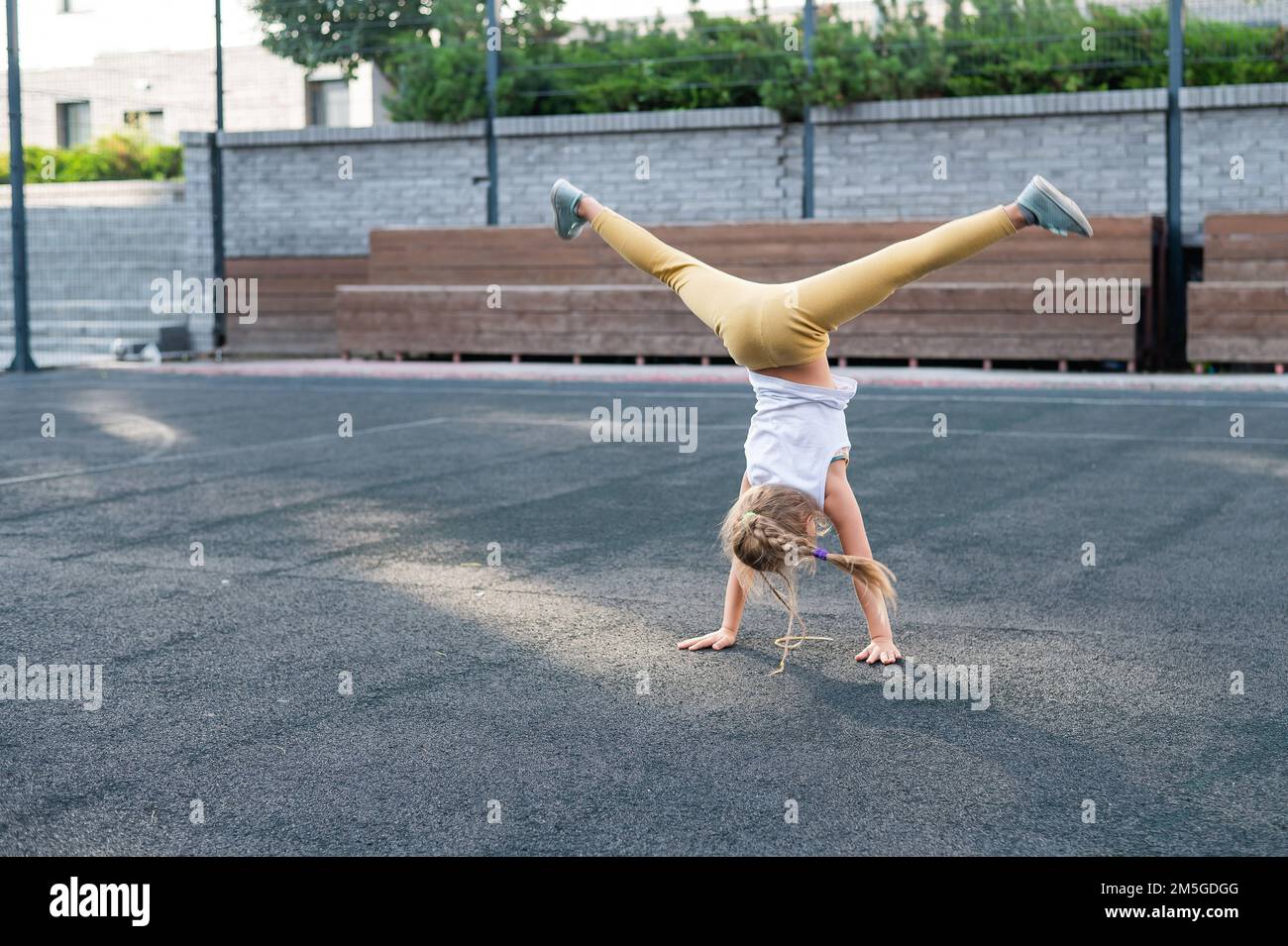Caucasian girl makes a cartwheel on the sports field outdoors.  Stock Photo