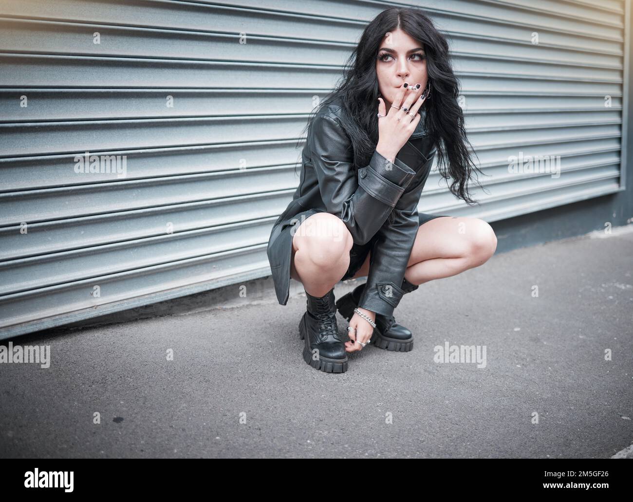 Punk, emo and woman smoking a cigarette in the street of an urban city in Canada in an edgy black outfit. Grunge, rocker and girl smoker with tobacco Stock Photo
