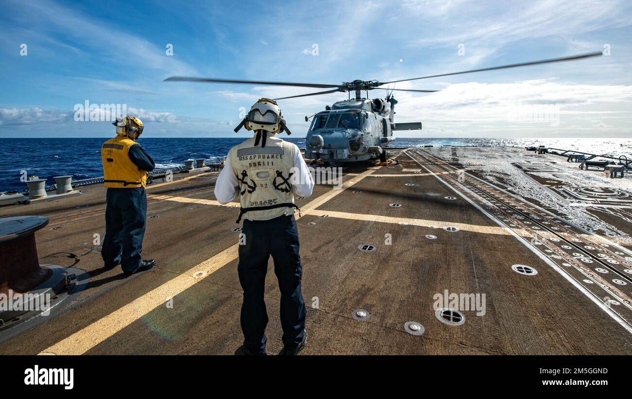 PHILIPPINE SEA (March 17, 2022) Boatswain’s Mate 2nd Class Jewlian Wilson, left, from Jacksonville, Fla., and Boatswain’s Mate 2nd Class Scott Wright, from Sylvania, Ala., stand watch as an MH-60R Sea Hawk helicopter, assigned to the “Raptors” of Helicopter Maritime Strike Squadron (HSM) 71, prepares to launch from the flight deck of Arleigh Burke-class guided-missile destroyer USS Spruance (DDG 111). Abraham Lincoln Strike Group is on a scheduled deployment in the U.S. 7th Fleet area of operations to enhance interoperability through alliances and partnerships while serving as a ready-response Stock Photo