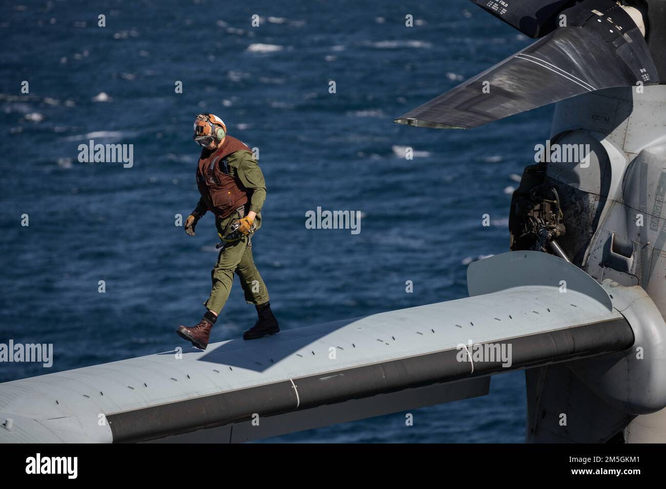 ATLANTIC OCEAN – Lance Cpl. Grant Bishop, a MV-22 mechanic assigned to Marine Medium Tiltrotor Squadron (VMM) 263, 22nd Marine Expeditionary Unit (MEU), walks the wing of a MV-22 Osprey aboard the Wasp-class amphibious assault ship USS Kearsarge (LHD 3) March 17, 2022. The Kearsarge Amphibious Ready Group (ARG) and 22nd MEU are operating in the Atlantic Ocean in support of Naval operations to maintain maritime stability and security in order to ensure access, deter aggression and defend U.S., allied and partner interests. Stock Photo