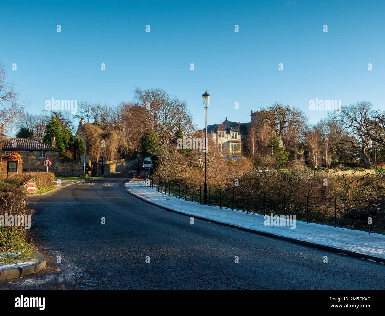 View of Duddingston Village Church and road leading towards Duddingston Village with snow on the footpath Stock Photo